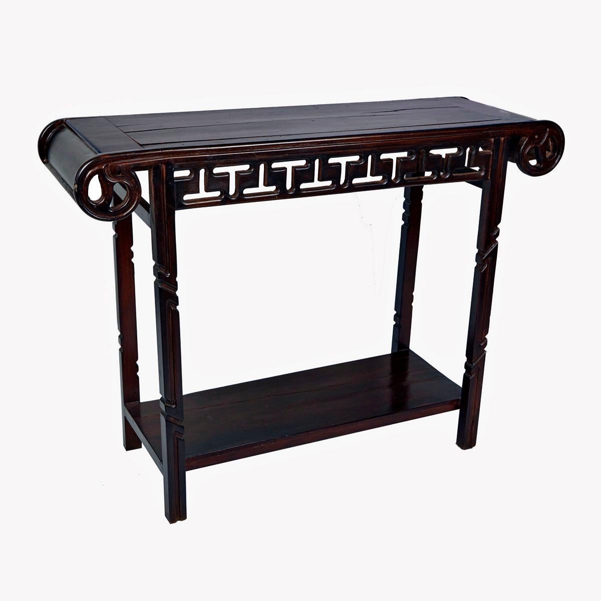 A lute top console table in dark-stained wood with carved details, latticed apron, turned legs and lower level shelf. Cambodia, Mid-20th Century. 