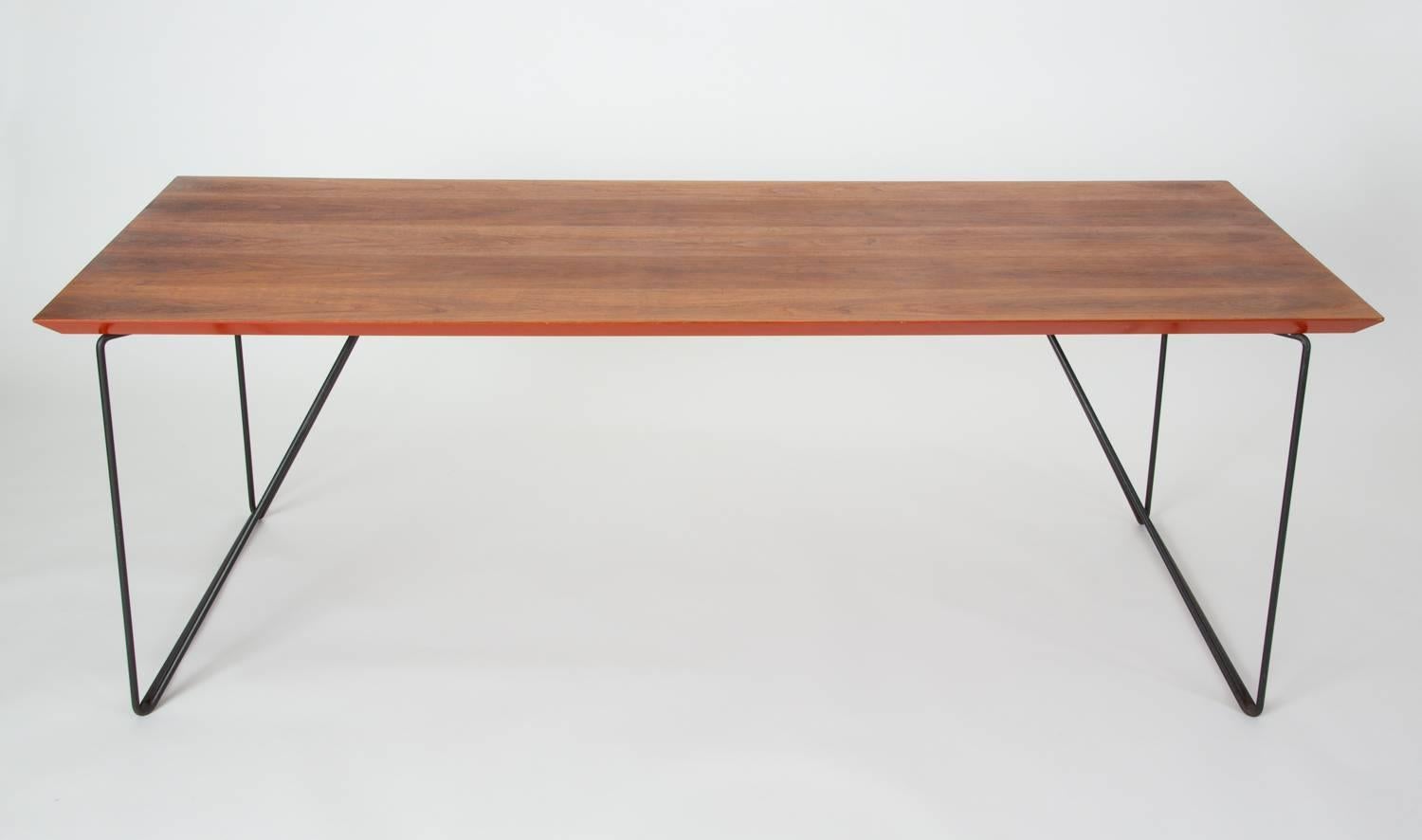 A long dining table, conference table, or desk by California designer Luther Conover. This example has Conover's distinctive polygonal legs - two angled frames in enameled steel - with a custom walnut surface. The tabletop has a back-bevelled edge