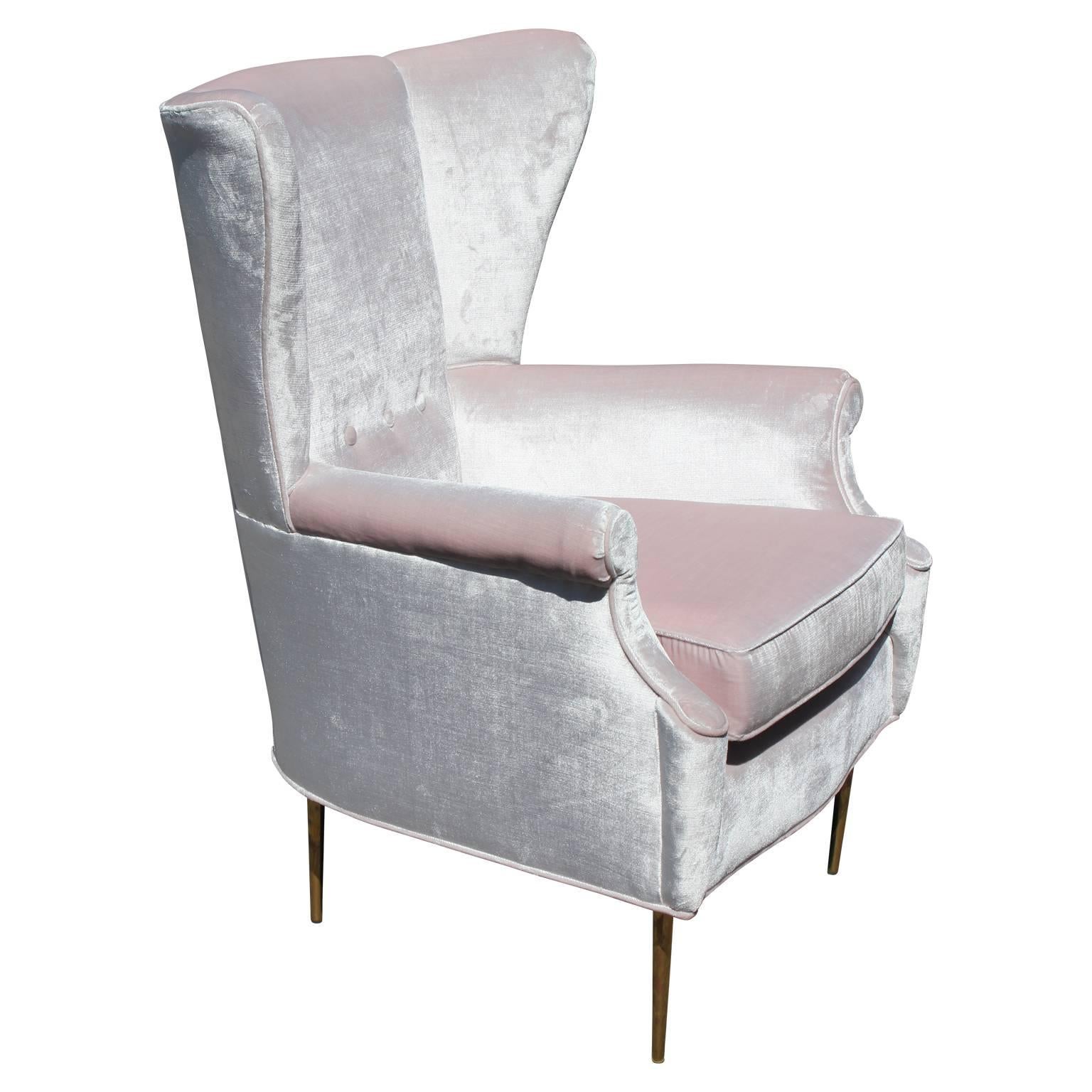 Glamorous pair of Italian wingback lounge chairs in the style of Paolo Buffa. Chairs are freshly upholstered in an ultra luxe, pale pink velvet. Slim tapered brass legs finish the chairs.