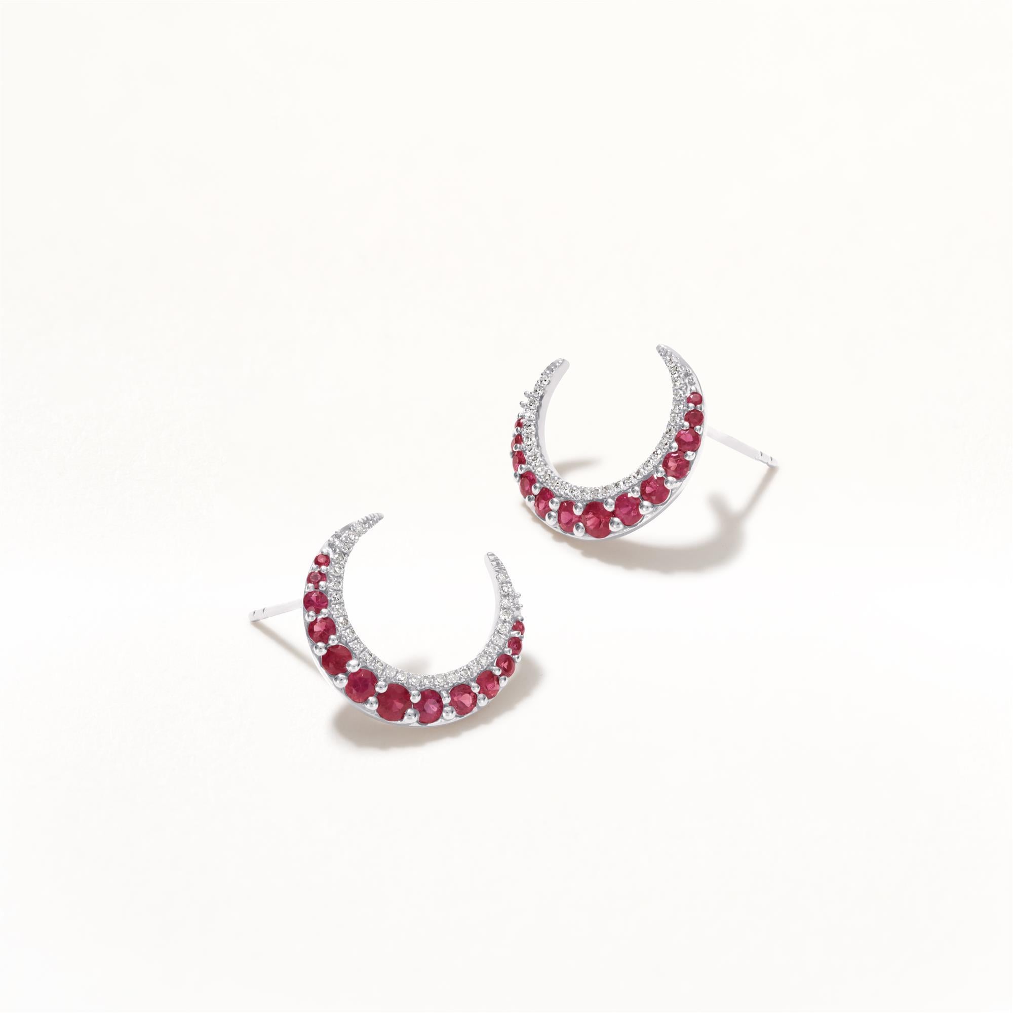 These stunning crescent moon earrings showcase a captivating design, beautifully adorned with a shimmering array of rubies and diamonds. The delicate crescent moon shape, featuring two rows, highlights an outer row of vibrant rubies arranged in