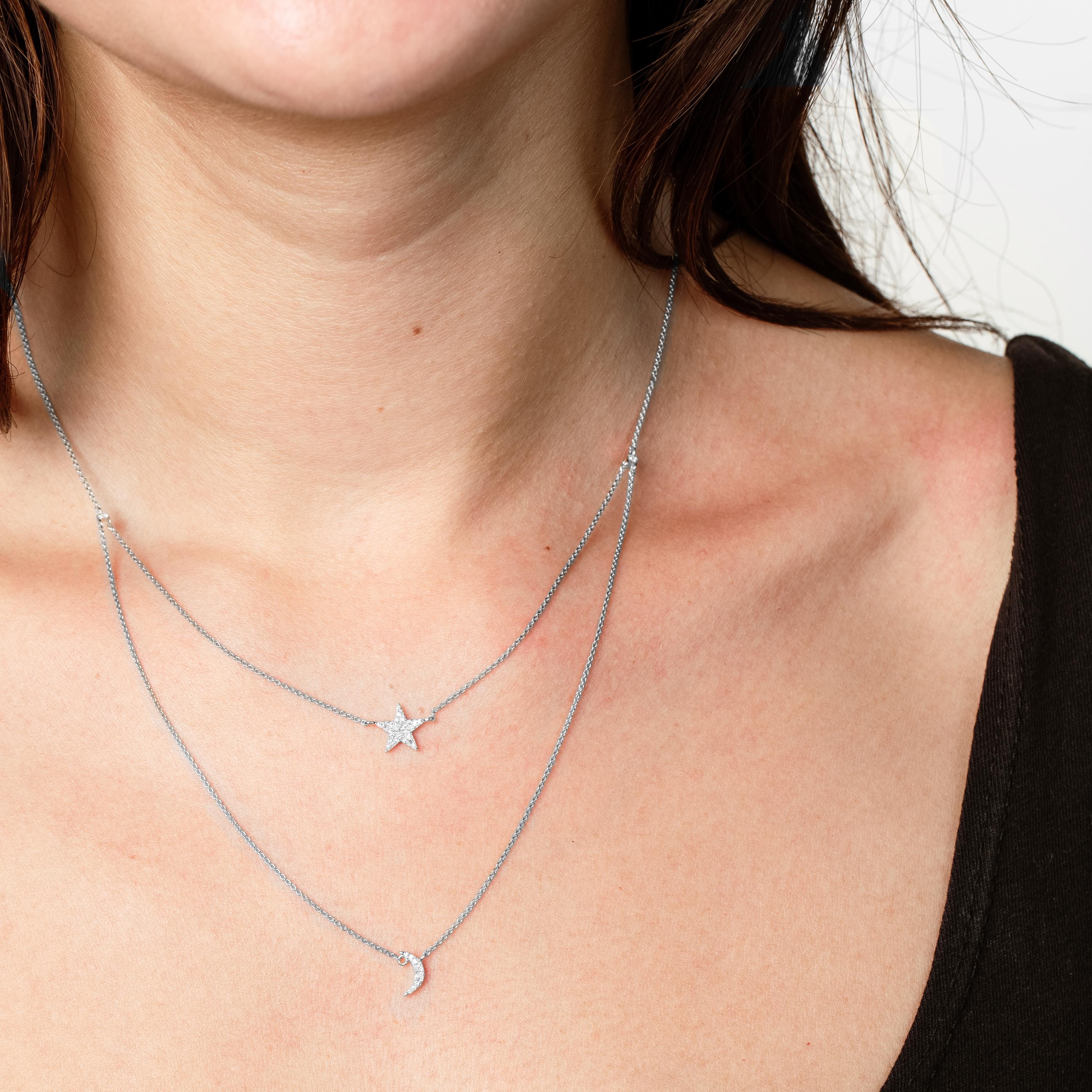 This celestial-inspired 14K gold necklace features two layers, the upper layer showcases a delicate star, while the lower layer highlights a beautiful crescent moon, both symbols of celestial beauty. Each piece is meticulously adorned with round,