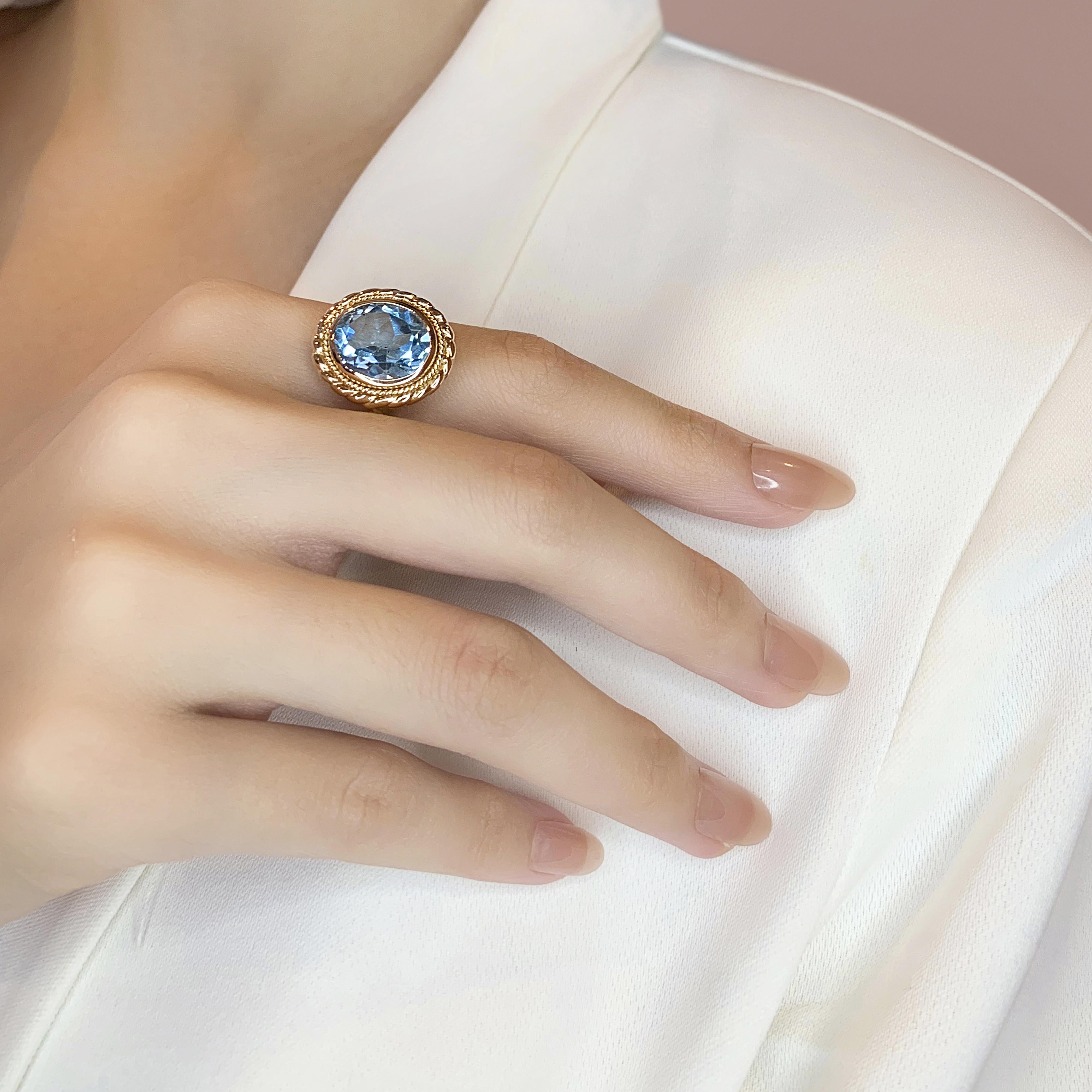 Offrez-vous une élégance luxueuse avec cette magnifique bague, réalisée en or jaune 18 carats. La pièce maîtresse est une étonnante topaze bleue de 10,2ct de forme ovale, qui rayonne d'une teinte riche et vibrante. Cette pièce remarquable a un poids