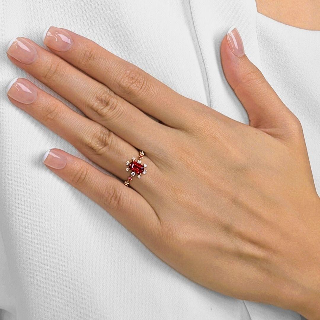 Cette bague rayonnante est une célébration de la couleur et de l'artisanat, mettant en valeur un spinelle orange de 0,90ct taillé en émeraude qui brille d'un éclat ardent. Autour de la pièce maîtresse, 4 rubis ronds et brillants (0,08ct au total)