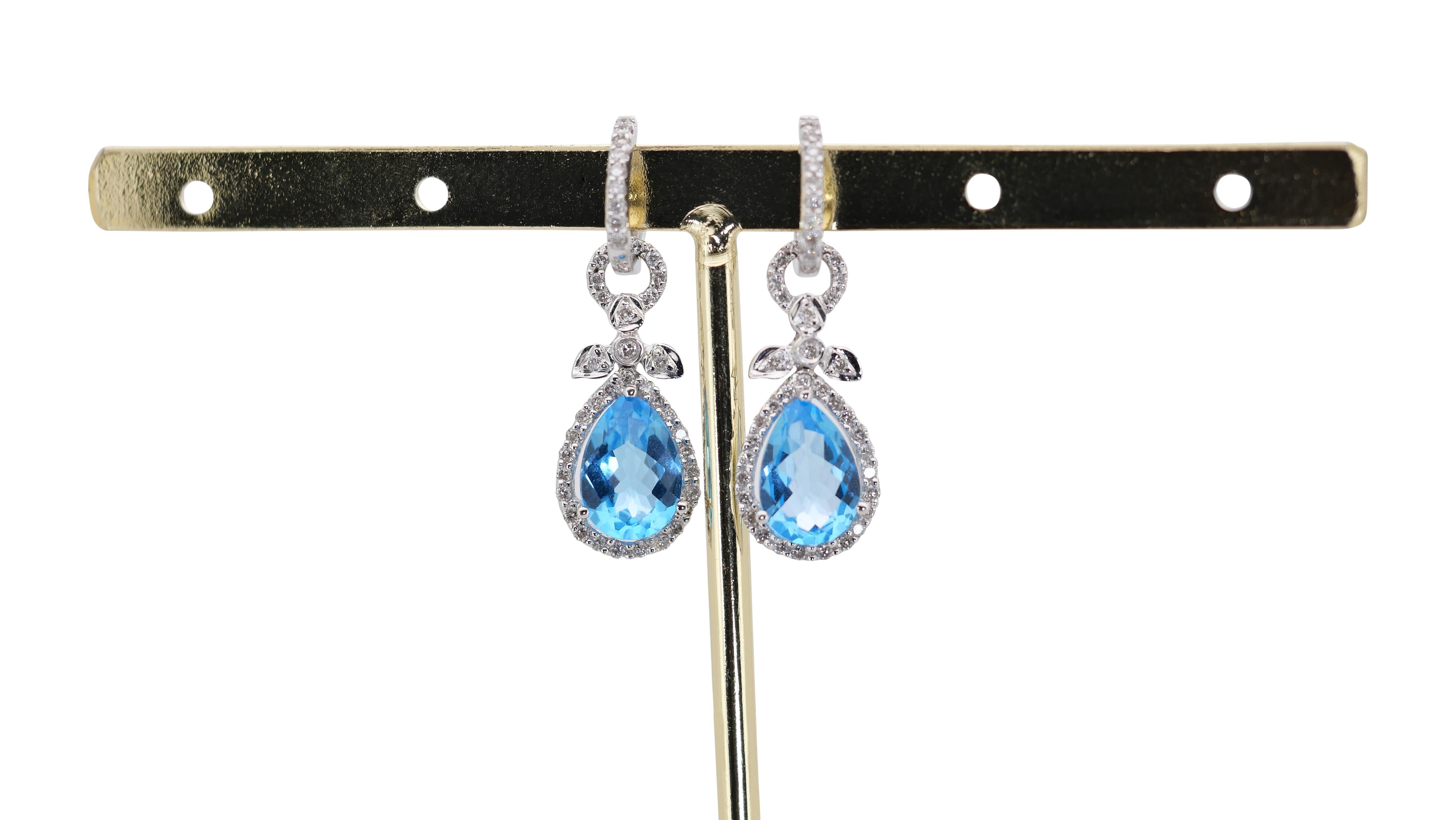 A stunning pair of dangle earrings with a dazzling 4.36 carat pear shape natural topaz. It has 0.64 carats of side diamonds which add more to its elegance. The jewelry is made of 18k white gold with a high-quality polish. It comes with a fancy