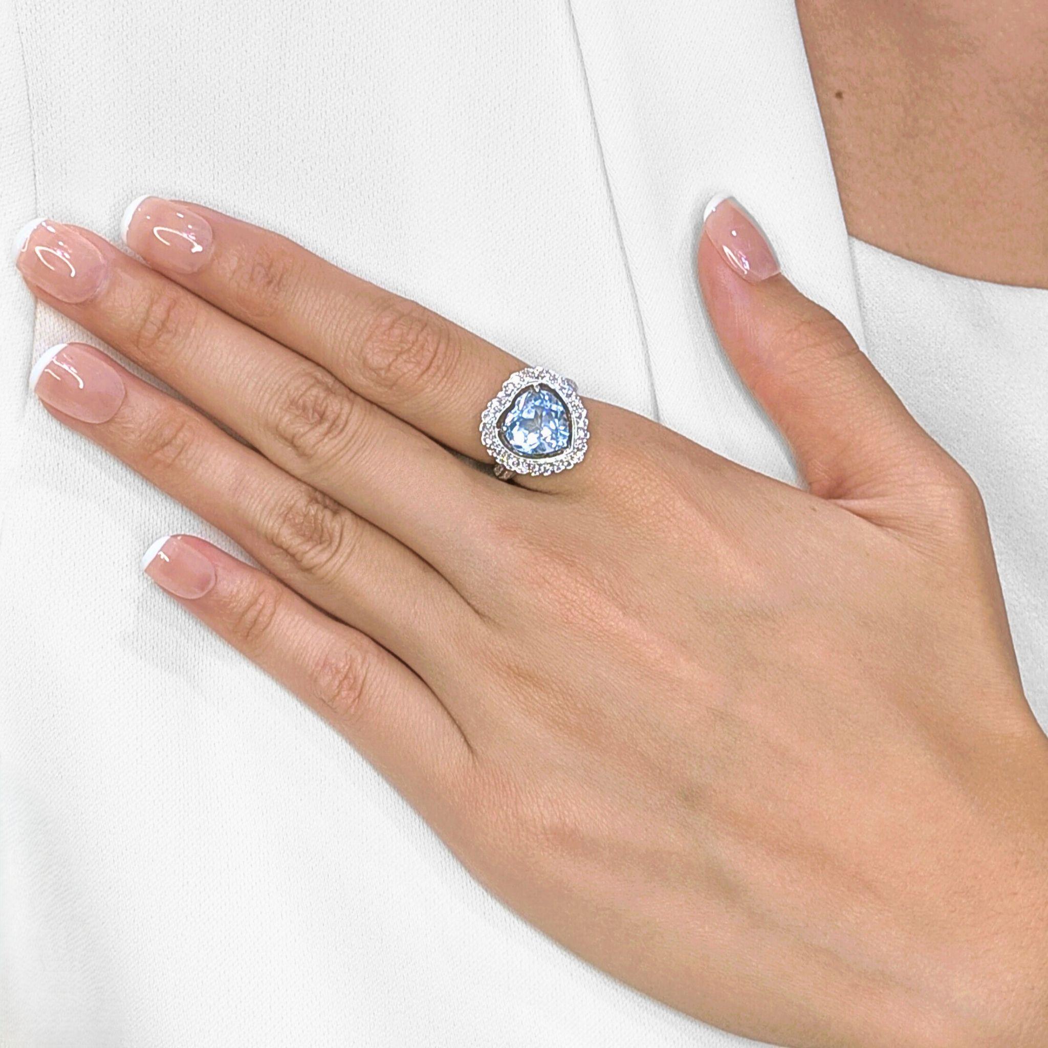 Questo affascinante anello mette in mostra uno splendido topazio azzurro a forma di cuore da 4,57 carati, che emana una morbida brillantezza che simboleggia eleganza e romanticismo. Incorniciato da 42 diamanti tondi brillanti naturali per un totale