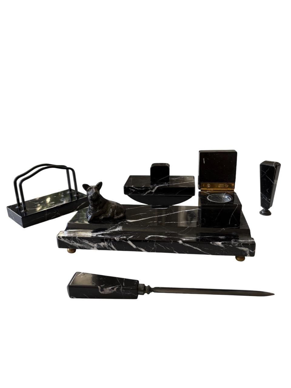 A luxurious Art Deco desk set in Swedish black marble with elegant white veining, dating from the 1930s. This refined ensemble includes a letter opener, rocker blotter, inkwell, letter rack, and a finely crafted sculpture of a reclining Scottish