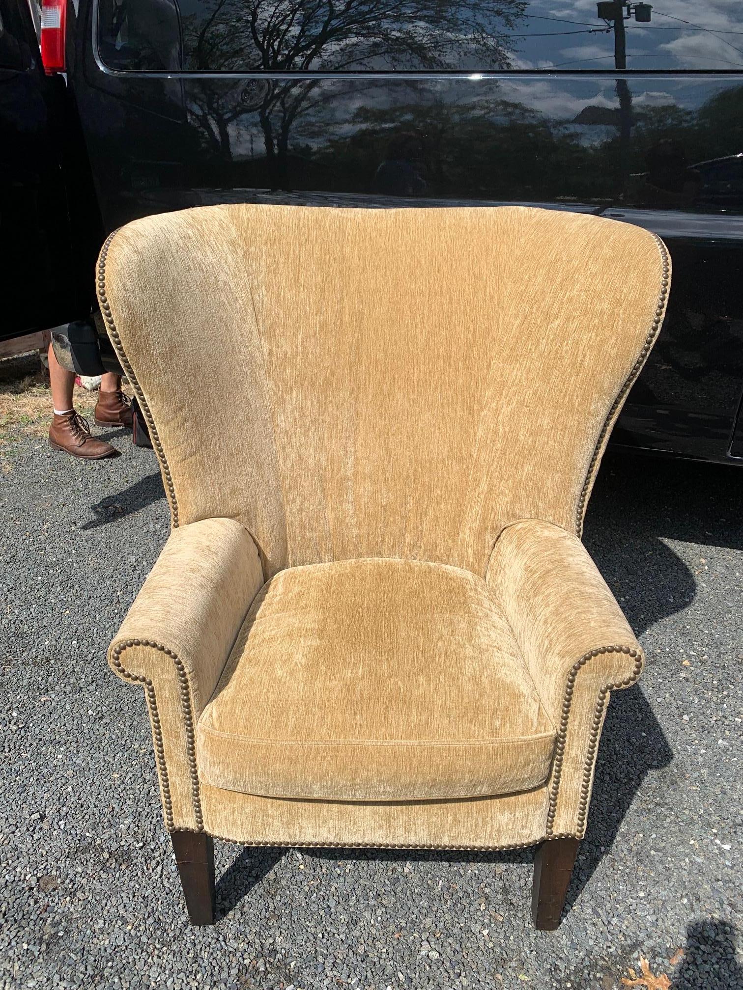 An inviting upholstered wing chair luxuriously outfitted in camel mohair velvet and finished with antiqued nailheads. Measures: Arm height 24.5 Seat depth 21
(JG).