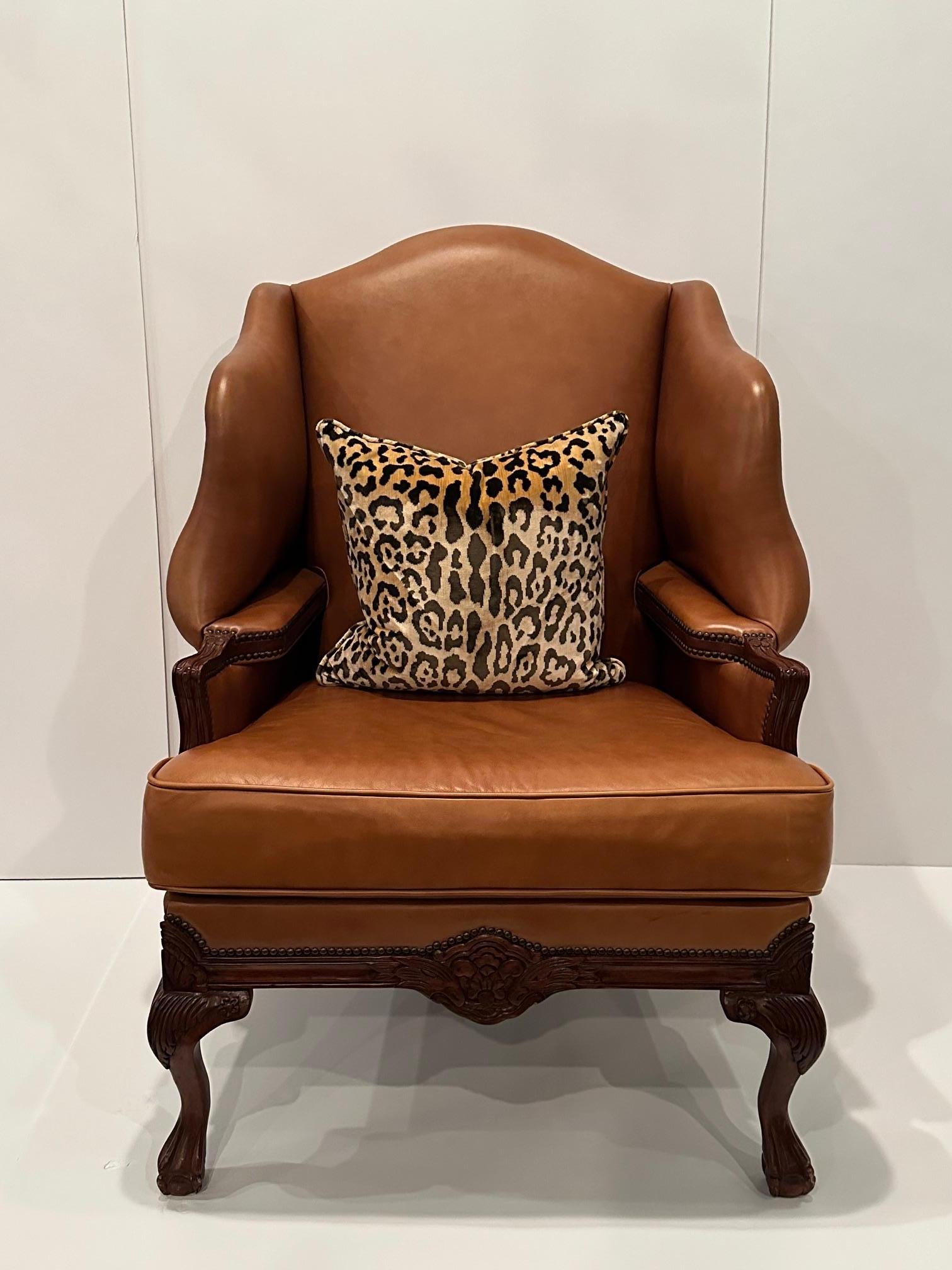 Luxurious large caramel leather wingback chair having mahogany carved legs and arms with enveloping interior elbow rests.  Handsome ball and claw feet.
Arm height 26.5
Between Interior armrests  23.5 w