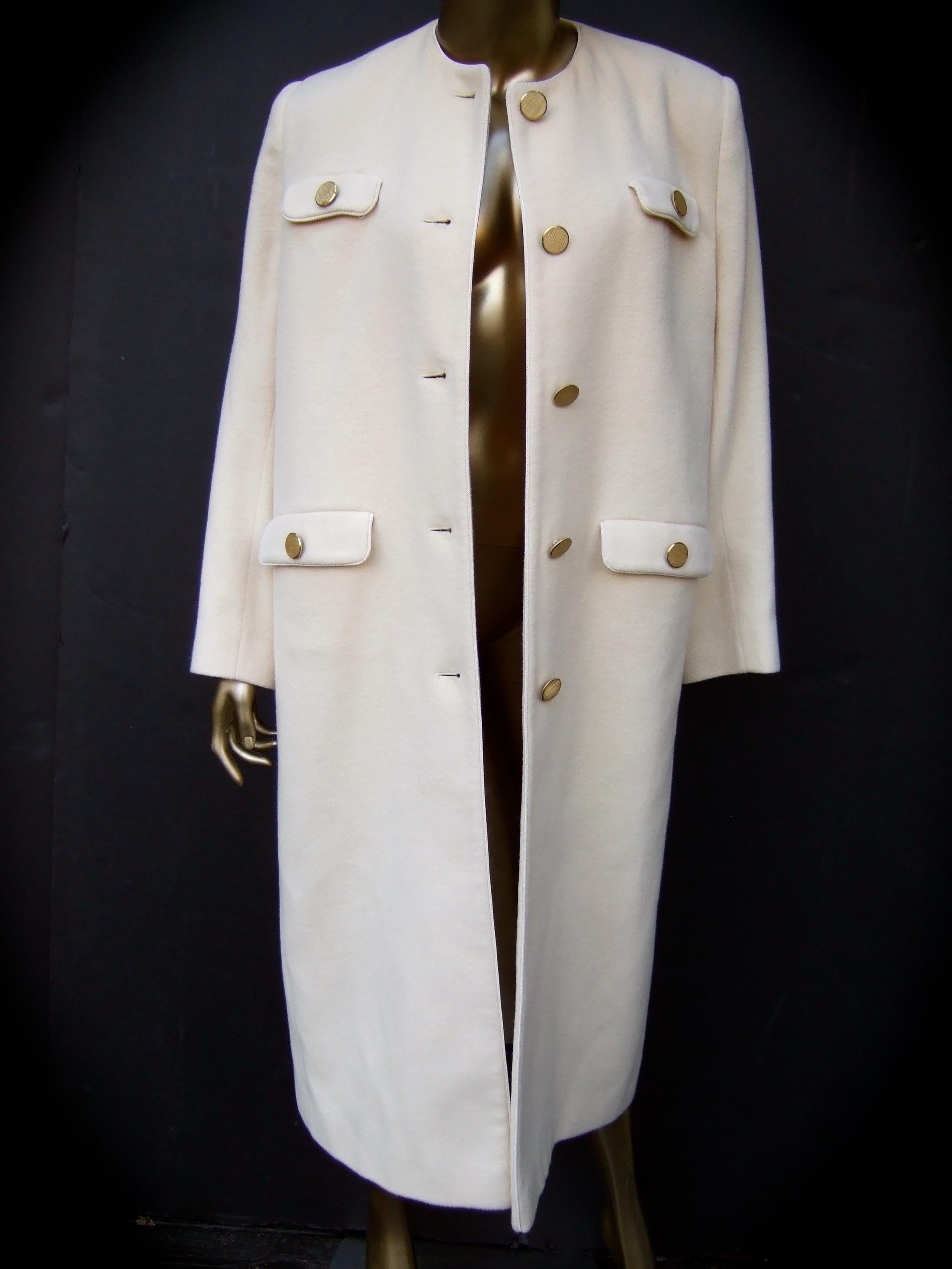 Luxurious cashmere creme winter white coat designed by Montaldo's c 1970s
The stylish coat is constructed with plush creme color cashmere 
Adorned with brushed matte gilt metal buttons that have a subtle military 
uniform influence 

Designed with a