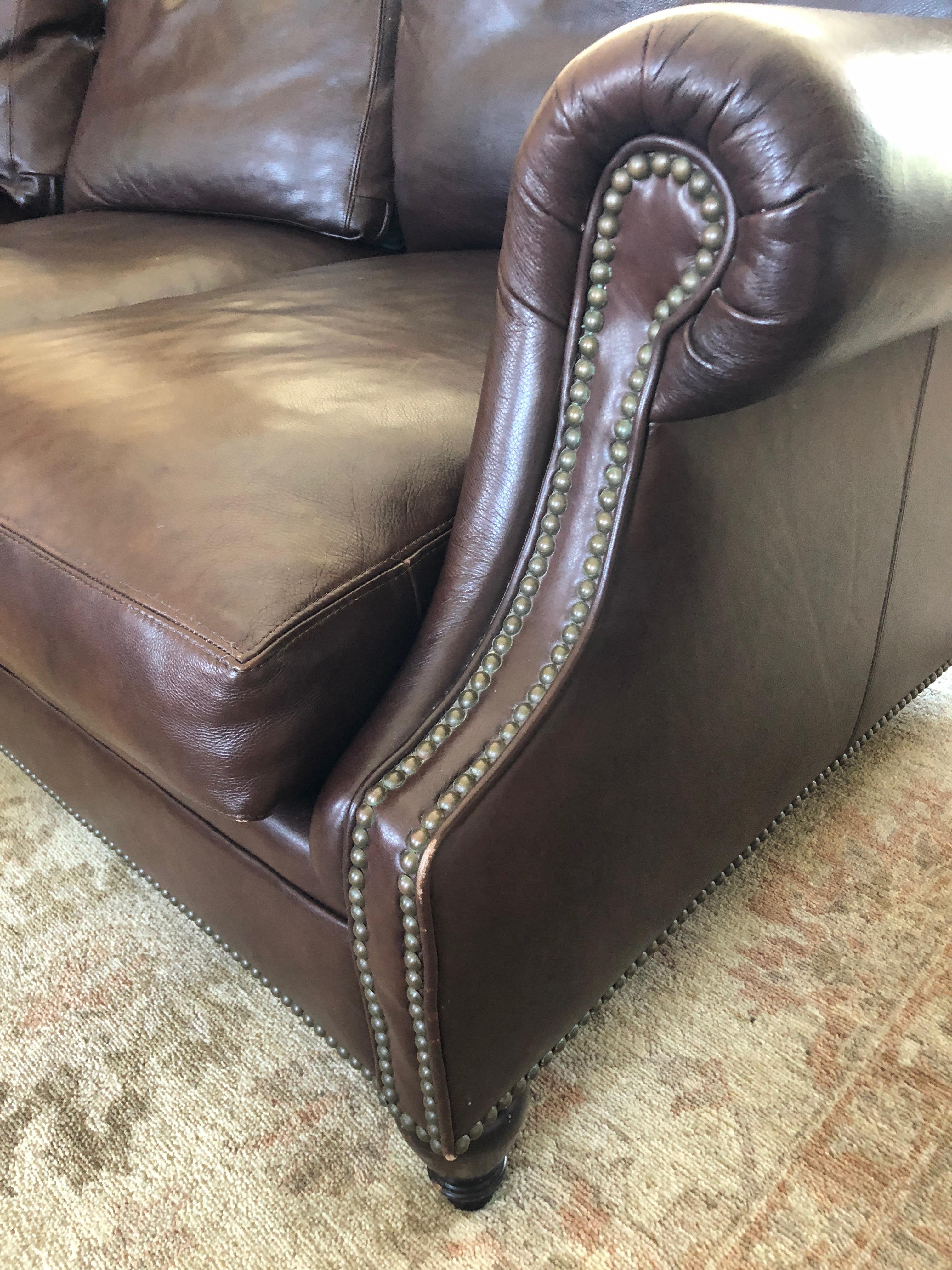 Sumptuous dark brown leather Chilton style Ralph Lauren sofa having 3 down wrapped foam core seat cushions and 3 down back pillows. Finished with muted brass nailheads. 
 Beautiful condition and craftsmanship. The leather is a dark brown and in