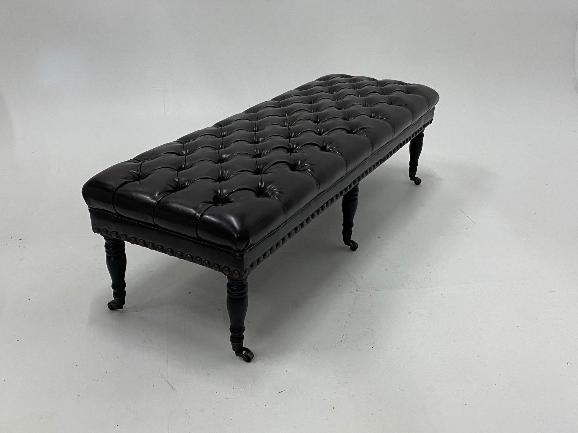 Very luxurious dark chocolate brown tufted leather bench ottoman having handsome turned mahogany legs on brass casters. Finished with large brass nailheads.