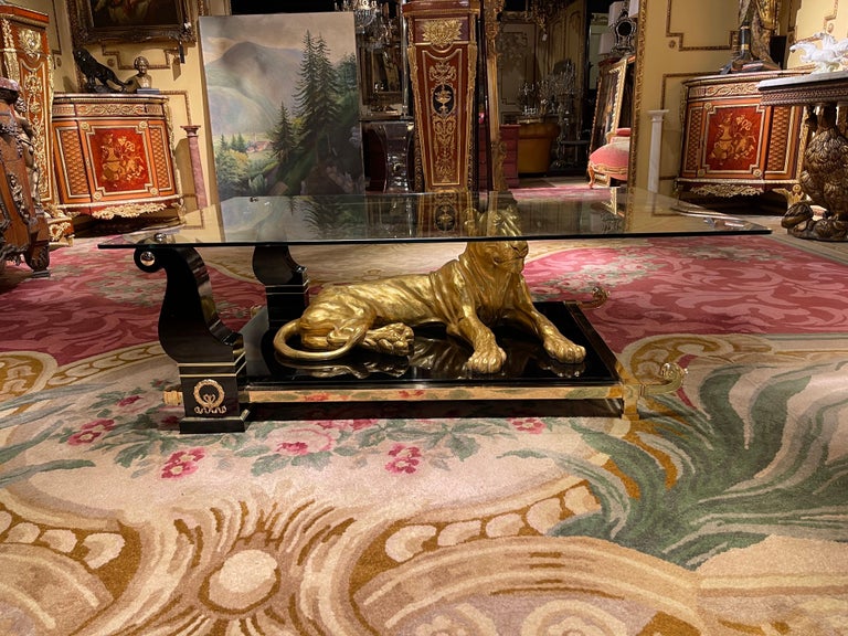 Extremely high quality designer coffee table. Sitting in the middle of the floor plate a life-size cat or panther in gold leaf. Faceted glass top connected with solid brass frame.
Tabletop made of wood in piano black.
Very decorative and an