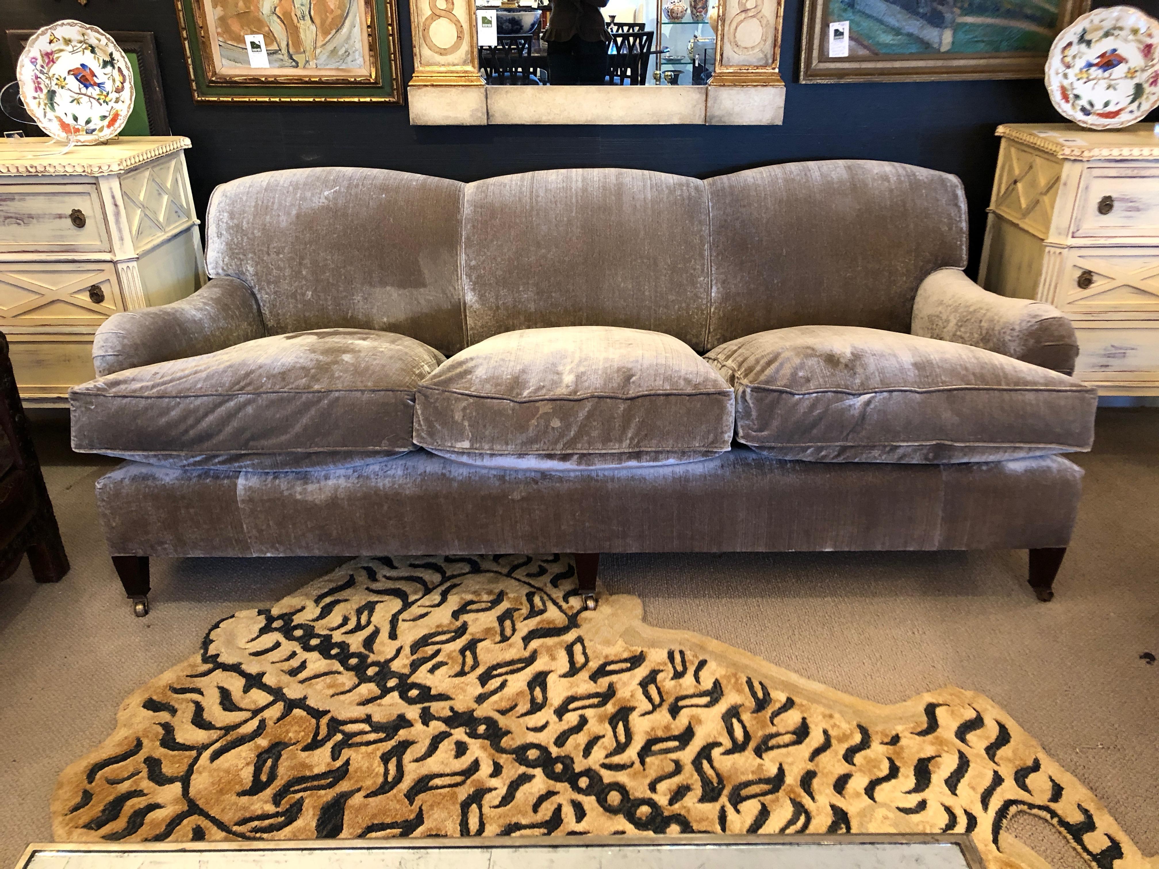 A custom top of the line very large George Smith Signature Collection sofa having fixed cushion back and three goose down filled luxurious seat cushions and laid back scroll arms. The upholstery is elegant taupe silk velvet. Mahogany feet and brass