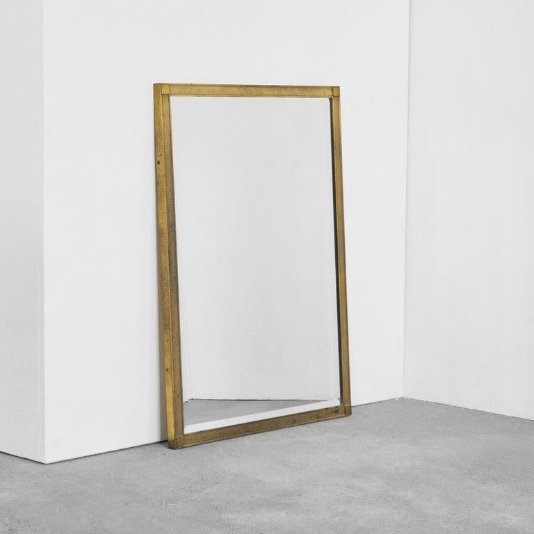 Luxueux miroir à facettes en laiton patiné. Europe, années 1960.    Ce luxueux miroir rectangulaire des années 1960 présente un cadre en laiton de haute qualité, avec des détails modestes et raffinés. Un motif subtil de fines lignes est visible sur