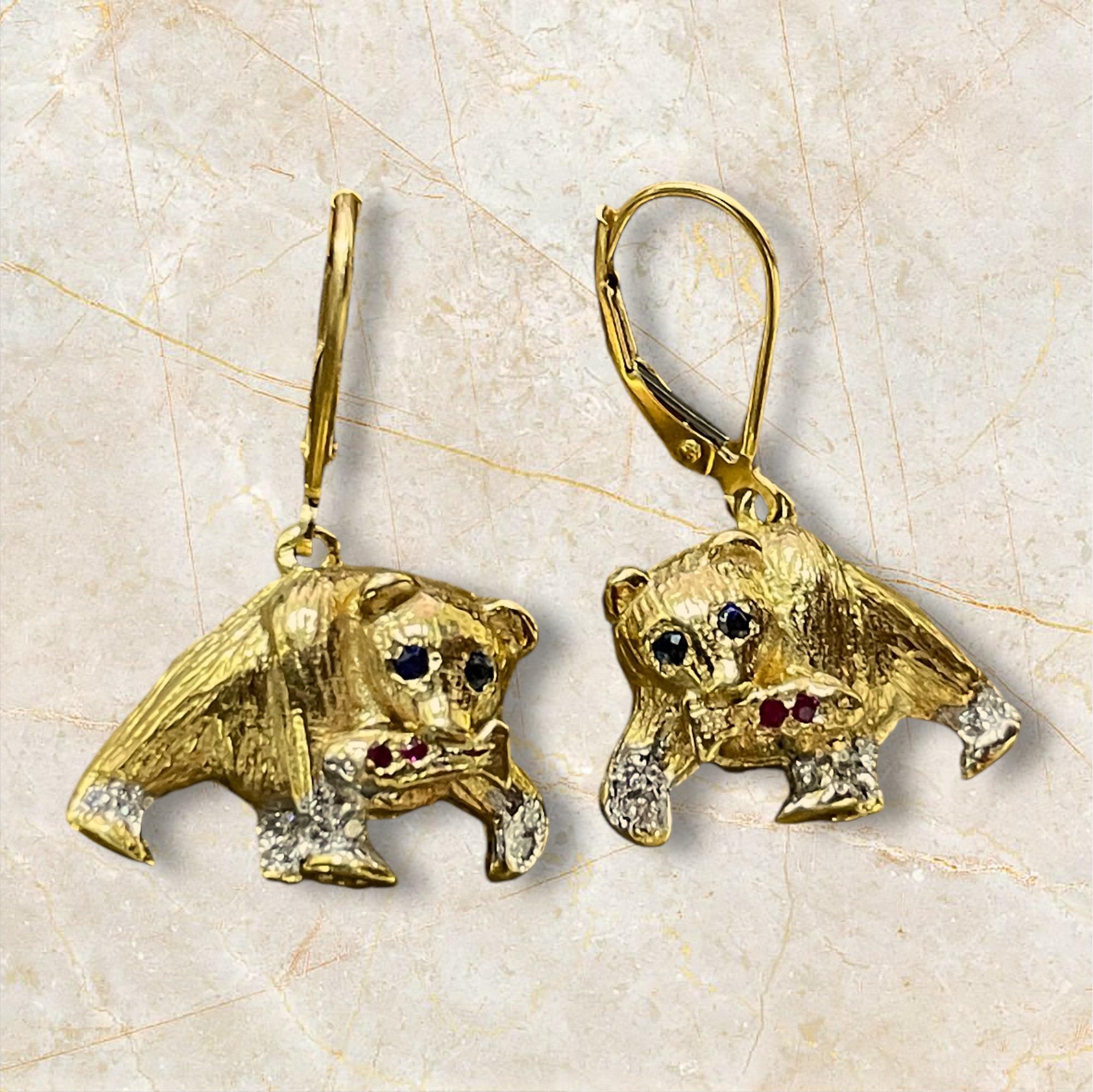 Estos adorables pendientes con forma de oso son la mezcla perfecta de elegancia y capricho. Fabricados en lujoso oro, los osos tienen brillantes ojos de zafiro y patas acentuadas con rubíes, que añaden un toque de color y sofisticación. El detallado