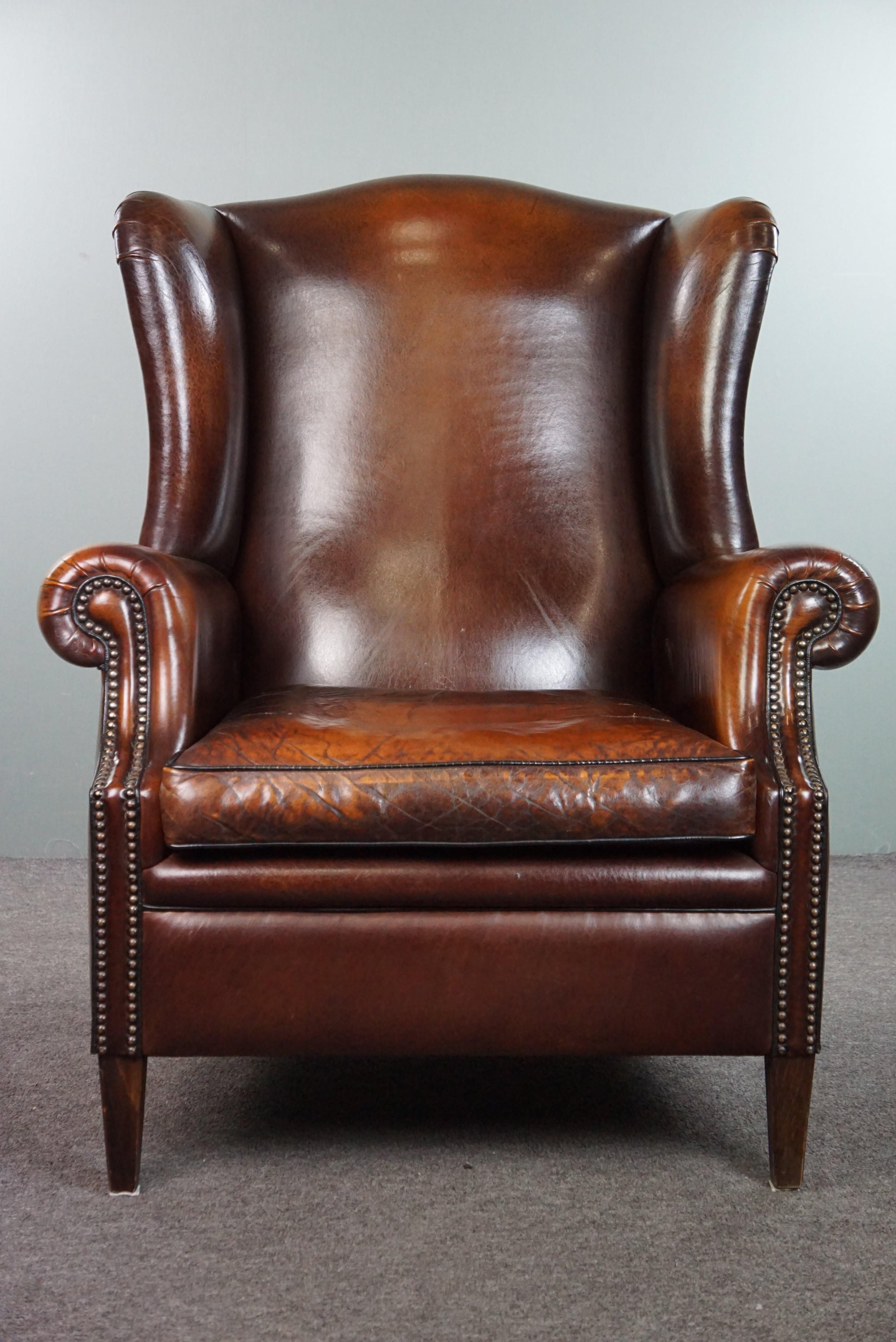 Nous vous proposons ce magnifique et luxueux fauteuil à oreilles en cuir de mouton aux couleurs étonnantes et à la patine remarquable, avec des têtes de clous décoratives. 

Pour ceux qui recherchent un fauteuil à oreilles en cuir de mouton