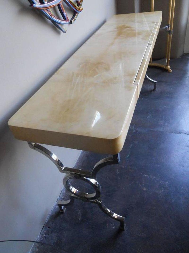 Luxurious parchment console table.
Chrome legs with parchment wood top.