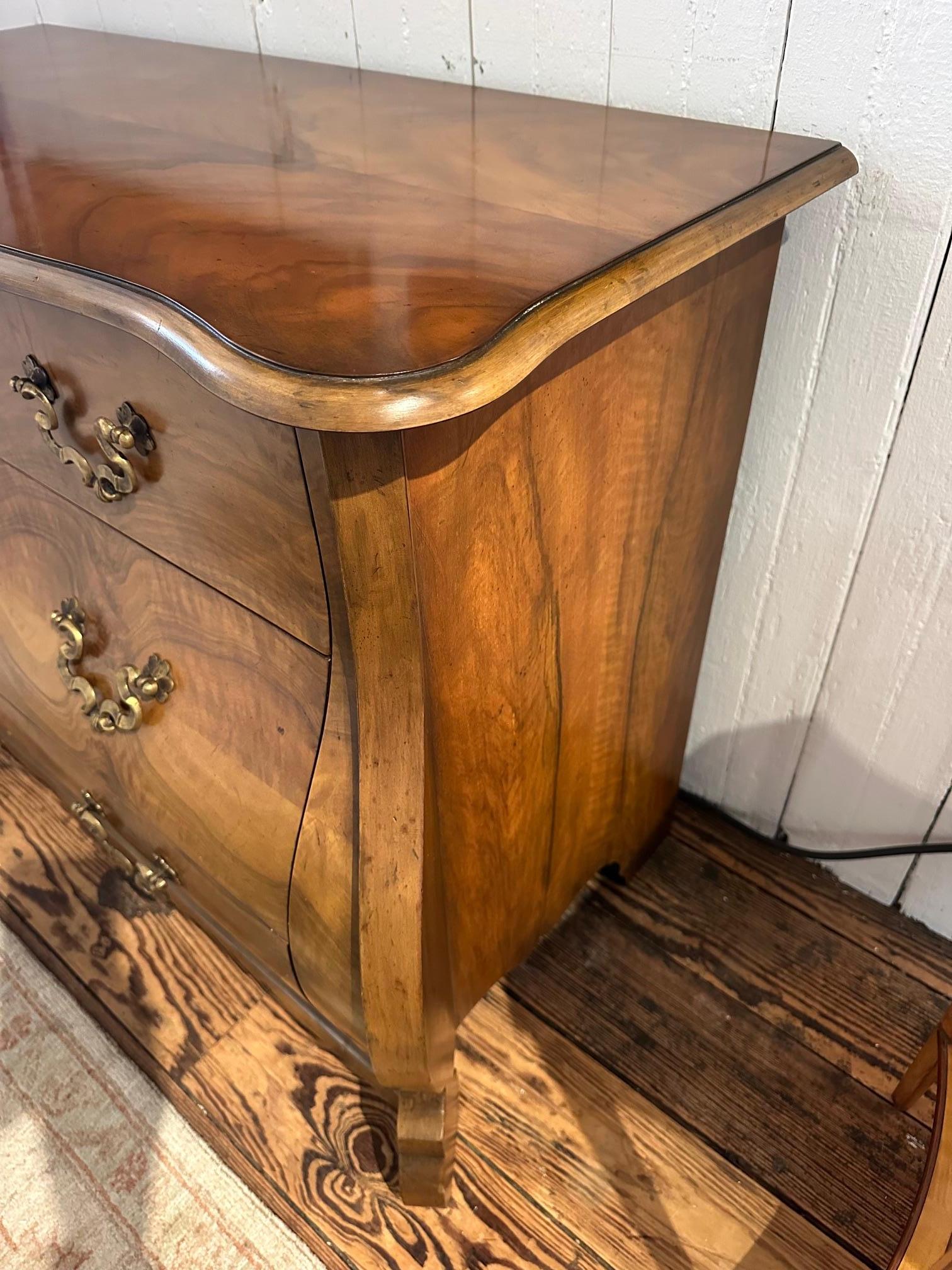 Preciosa cómoda serpentina de estilo Bombay con una magnífica factura de Baker Furniture Co.  Dos cajones medianos en la parte superior y dos cajones grandes en la parte inferior, todos con impresionantes herrajes originales de latón.

CD