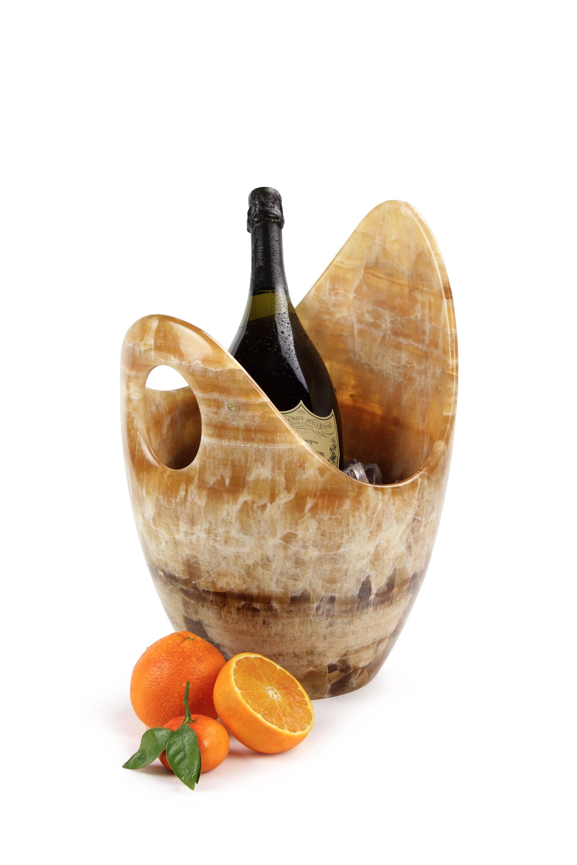 Luxurious Champagne bucket and two bowls sculpted by hand from a solid block of Amber Onyx. Polished finishing. 

Champagne bucket dimensions: L 28, W 29, H 41 cm. Available in different marbles, onyx and quartzite.
Oval bowl dimensions: L 45, W 22,