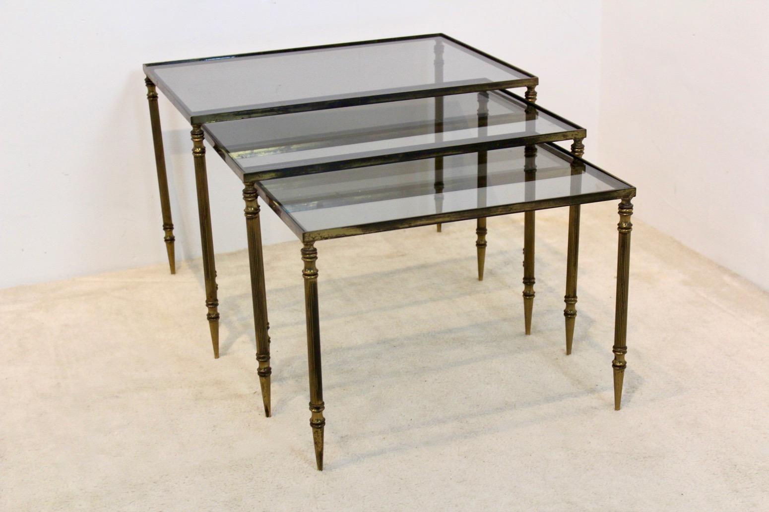 This gorgeous and elegant nest of three tables originates from France and was manufactured in the ‘70’s by Maison Charles. They feature a brass frame with dark glass on top. The brass frame has a nice patina due to age and use. A beautiful set of