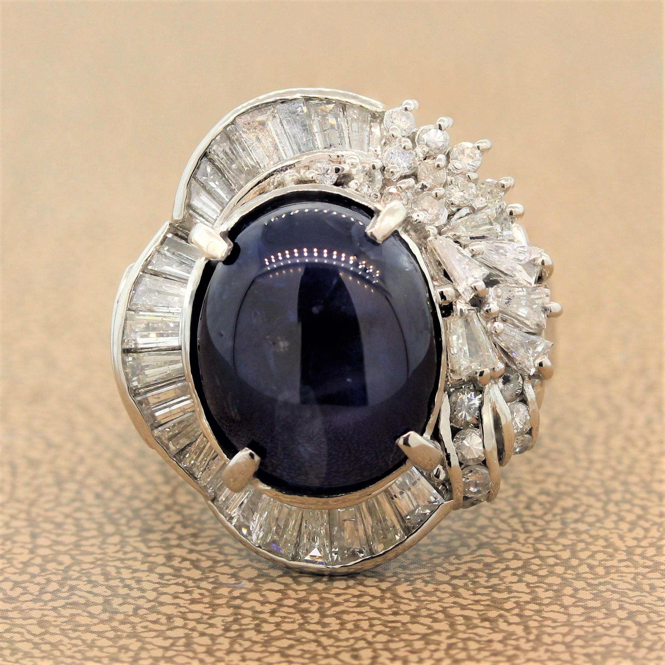 This deep blue 24.45 carat star sapphire is the star of the show. The cabochon star sapphire is haloed by an asymmetrical halo of diamonds. One side of the platinum ring is a ballerina design with baguette cut diamonds and the other side has a