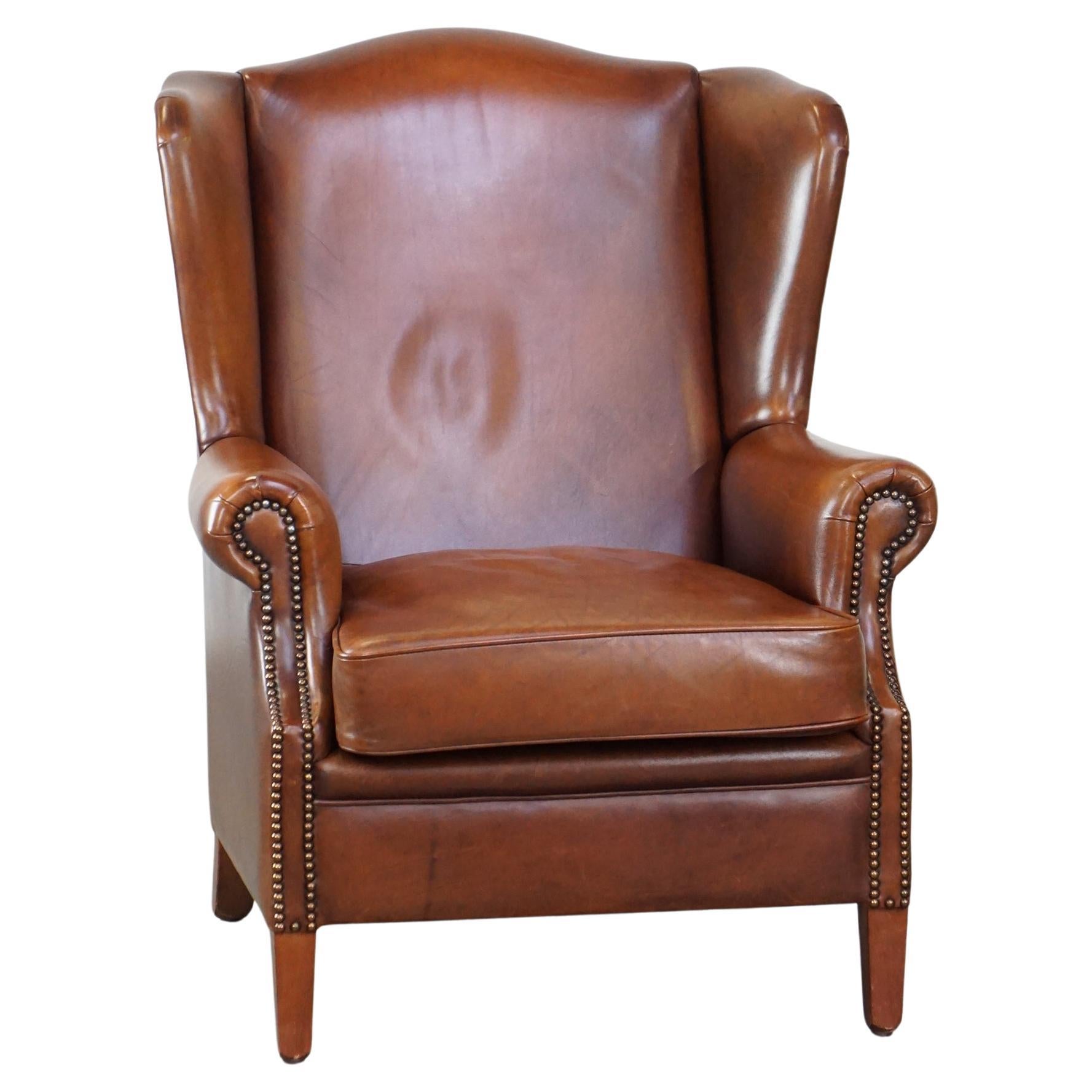 Luxurious, stately, wing chair made of cowhide in a beautiful warm cognac color