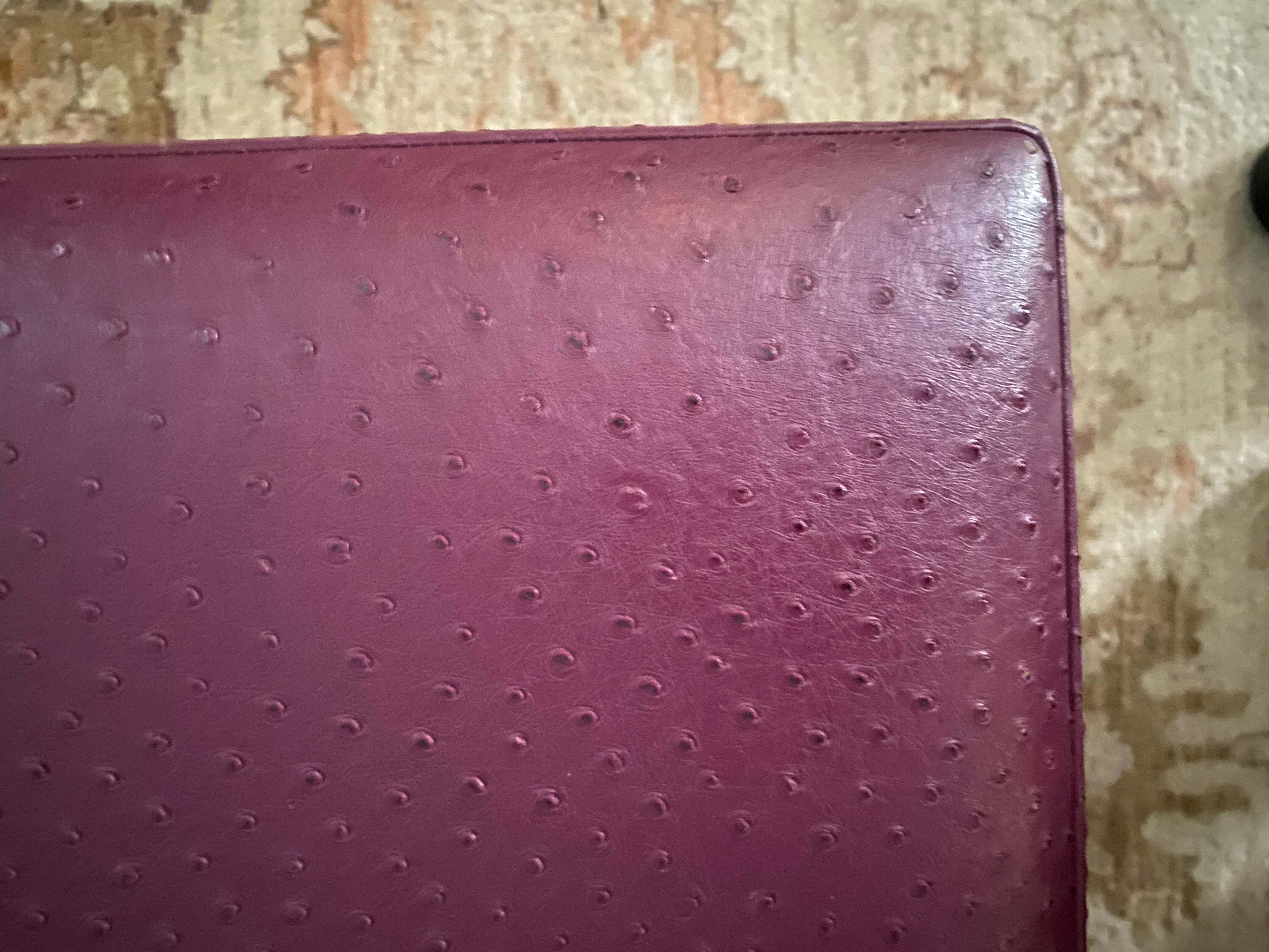 Pouf personalizzato molto grande e di grande effetto, rifinito con una morbida pelle testurizzata viola/bordeaux.  Un pezzo versatile e accattivante che può essere utilizzato anche come tavolino da caffè e seduta extra.  Quattro piedini di