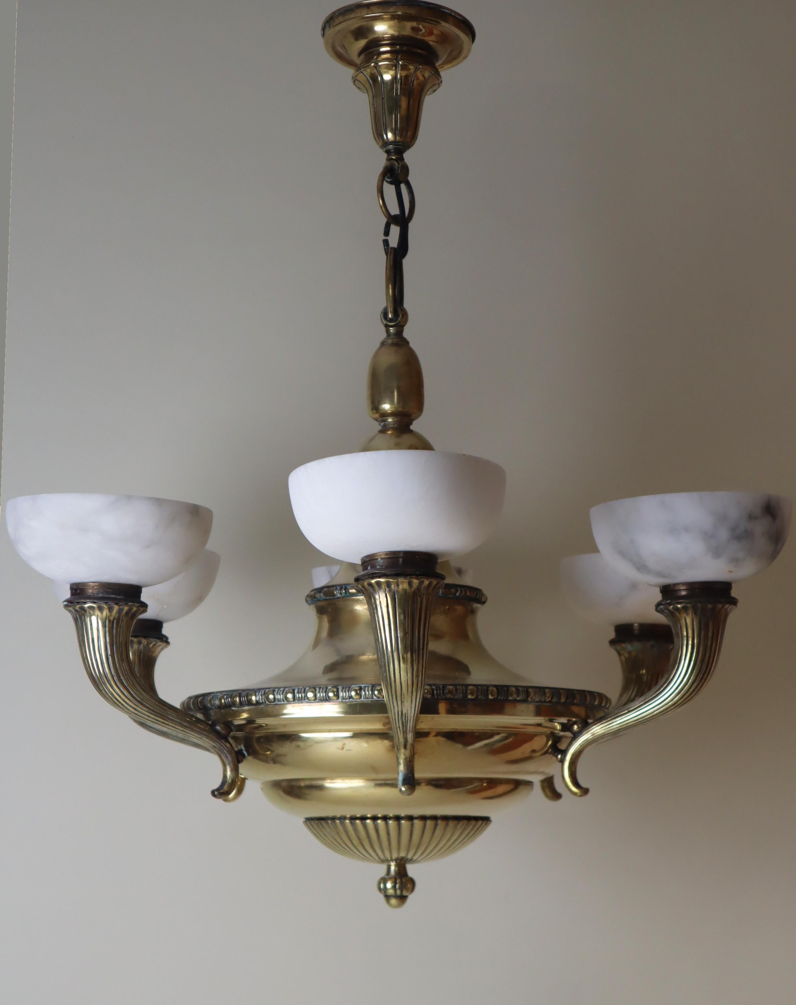 This exceptional, large chandelier is made of brass and alabaster. This masterful piece is special; its brass body reflects light from the bulbs into the room. The arms of the chandelier are modeled after a cornucopia and are cast in high-quality