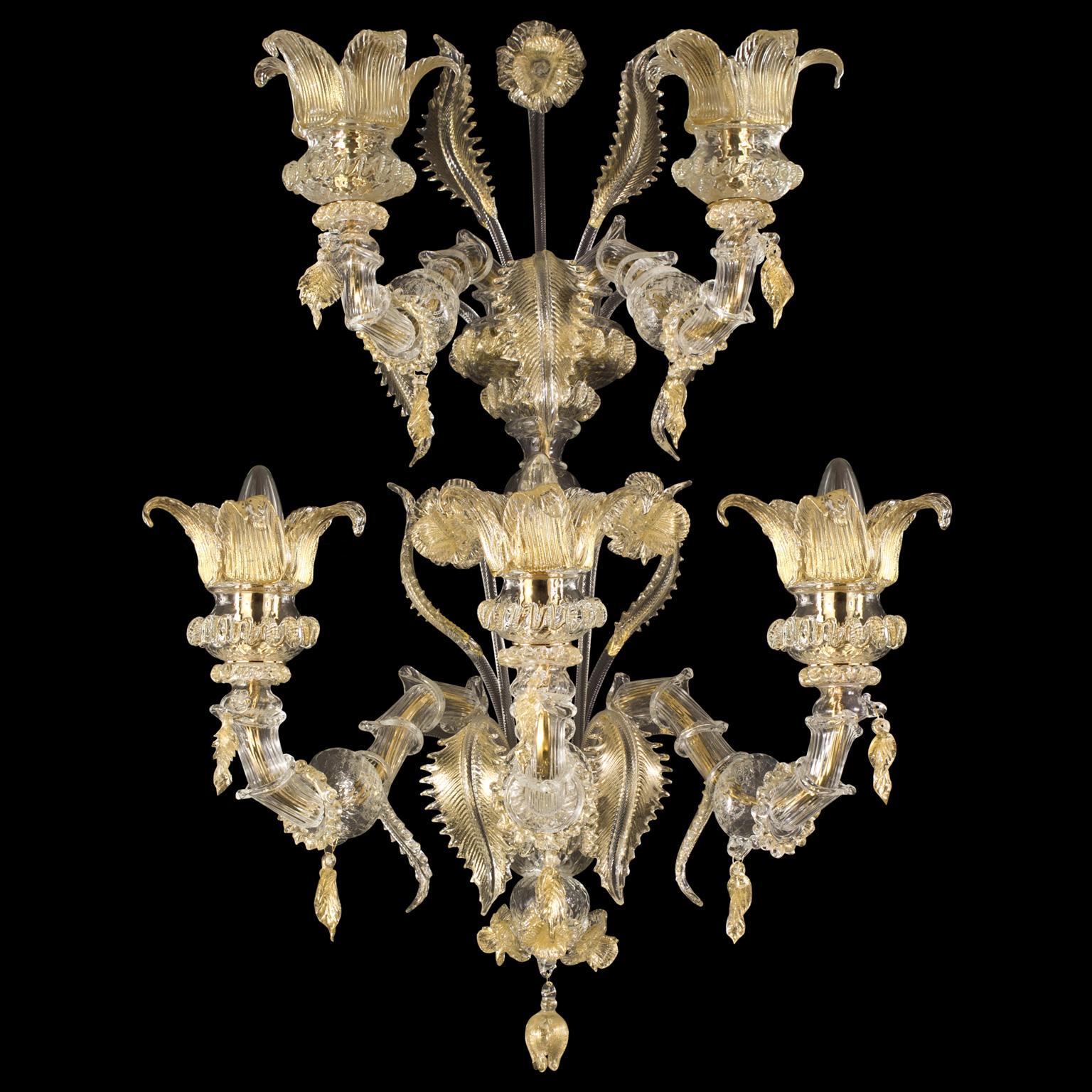 The Murano glass sconce Regale with 3+2 arms on 2 different levels is a romantic lighting work, inspired from the luxurious halls of the venetian buildings on the Canal Grande.
The colors, the floral decorations, the Rezzonico arms, the pendant