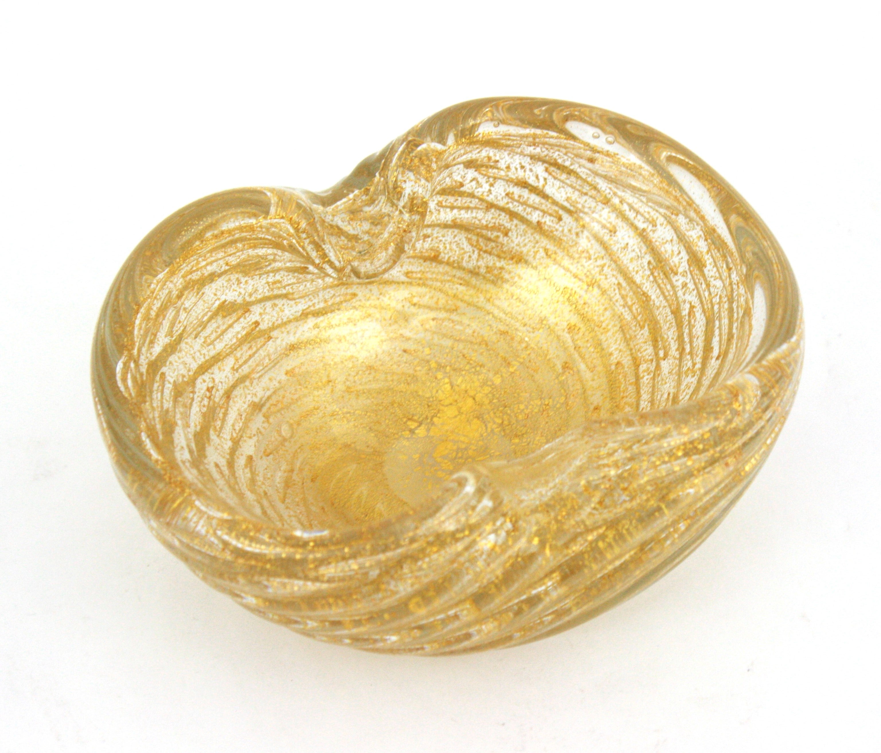 Cuenco, Cenicero o Vaciabolsillos de Cristal de Murano Remolino Moteado en Oro
Increíble cenicero o cuenco festoneado de cristal soplado de Murano con motas doradas de aventurina. Atribuido a Barovier e Toso, Italia, década de 1950.
Tiene burbujas