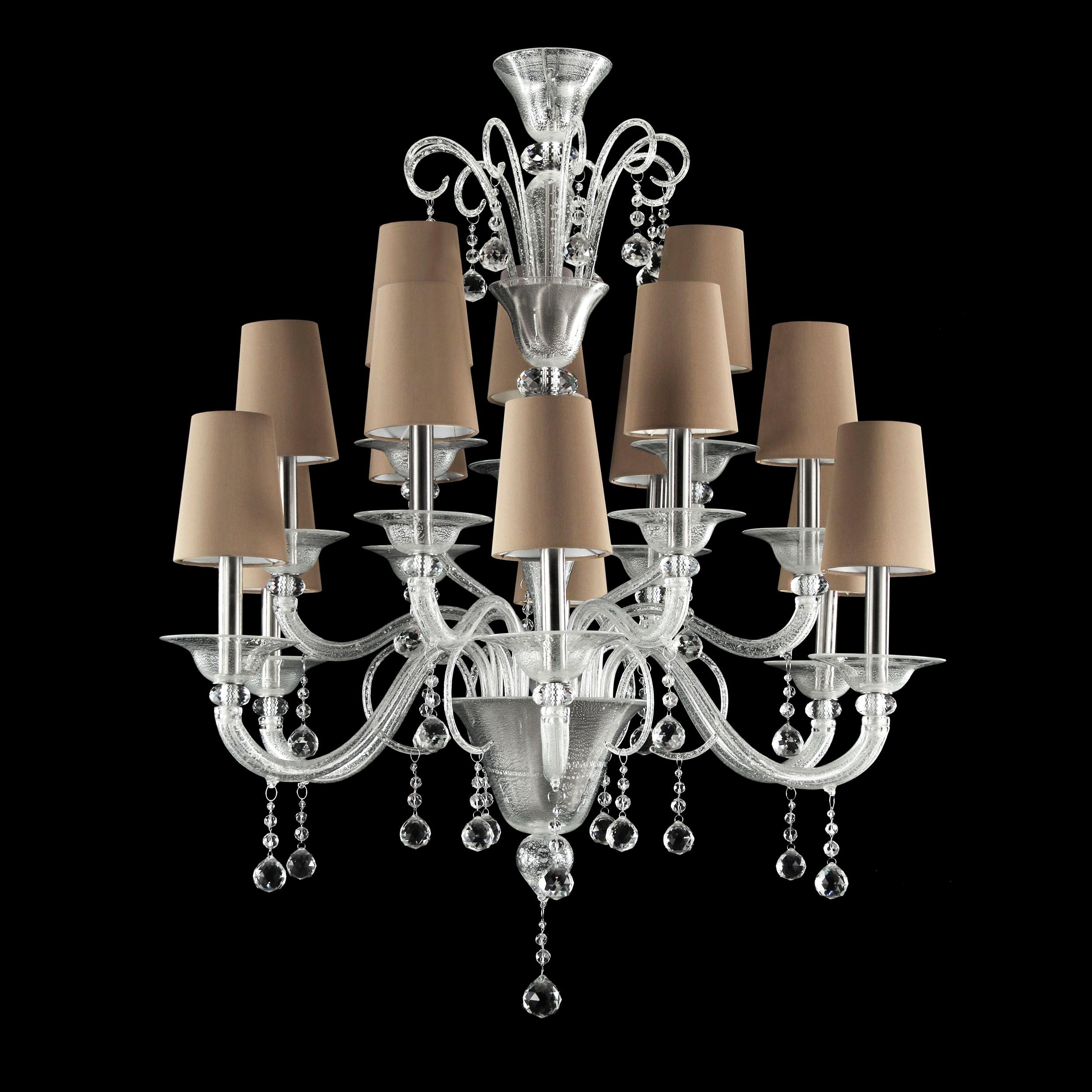 The luxury chandelier THE MOON is characterised by glass elements, curls, Swarovski® pendants and fabric lampshades. The arms and curls are in clear glass with silver leaf, the pendants in cut crystal and the lampshades are made from a refined cream