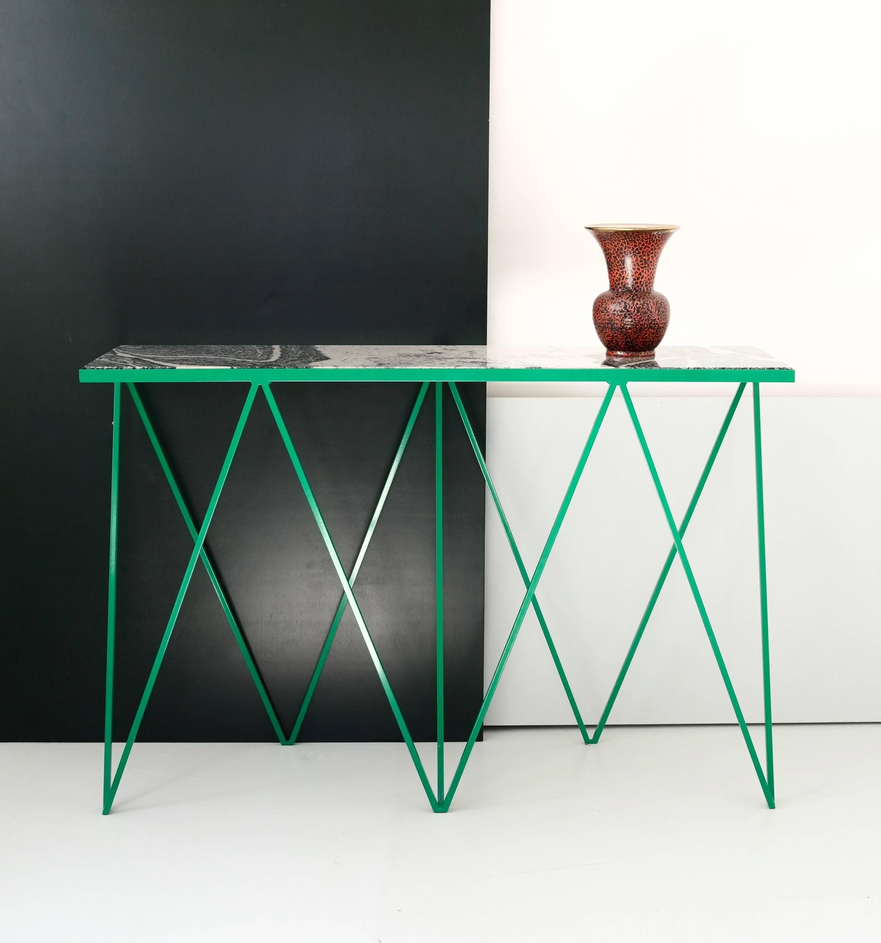 Esta mesa consola Jirafa está fabricada con una estructura de acero con recubrimiento en polvo de color verde brillante y un llamativo  encimera de piedra de granito. Cada mesa está hecha a mano y cada pieza de granito se selecciona cuidadosamente,