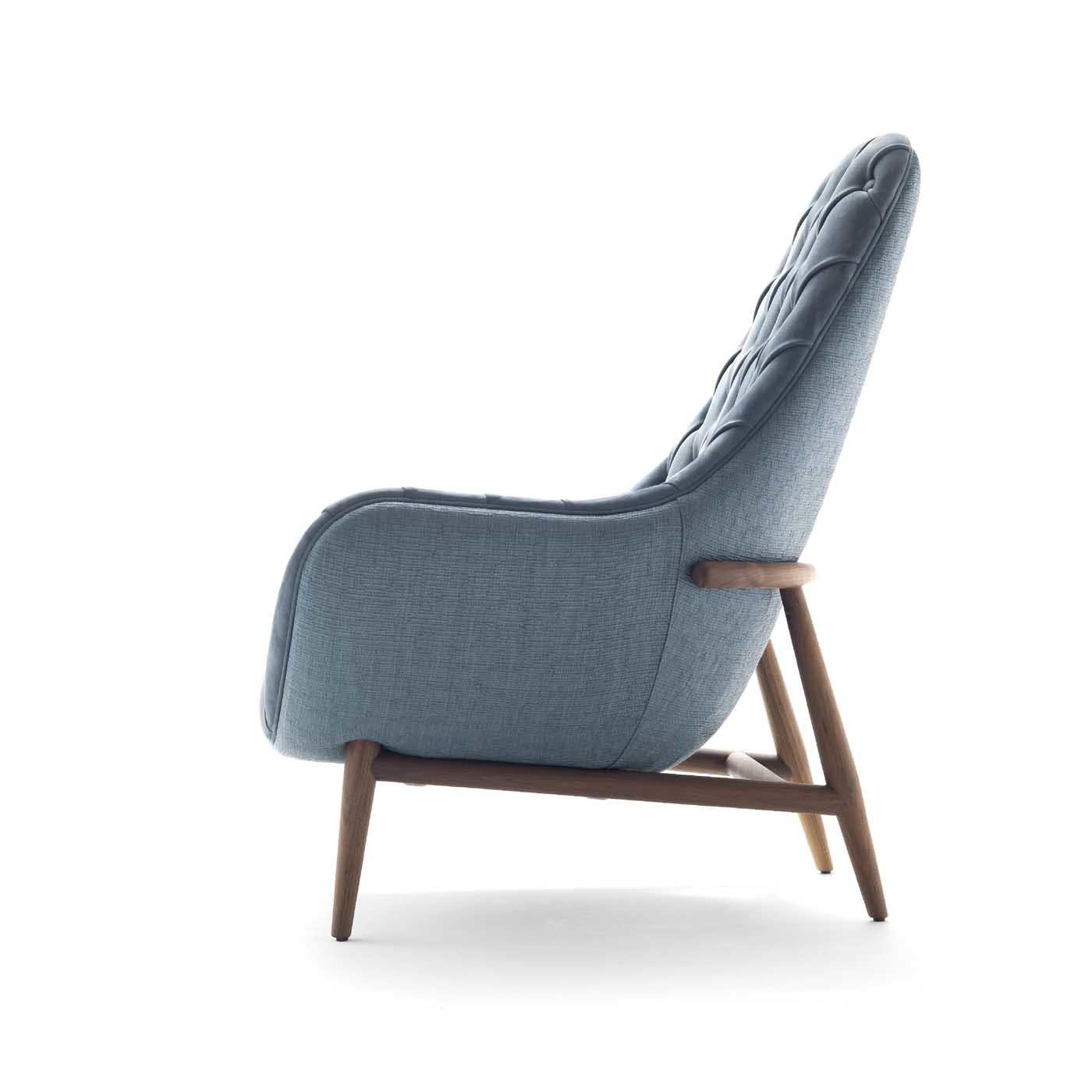 This elegant armchair combines the charming curves of mid-century design with an elegant tufted texture adorning the enveloping high back and diagonal armrests. Comfortable and welcoming, this silhouette is an ideal addition to a modern study or