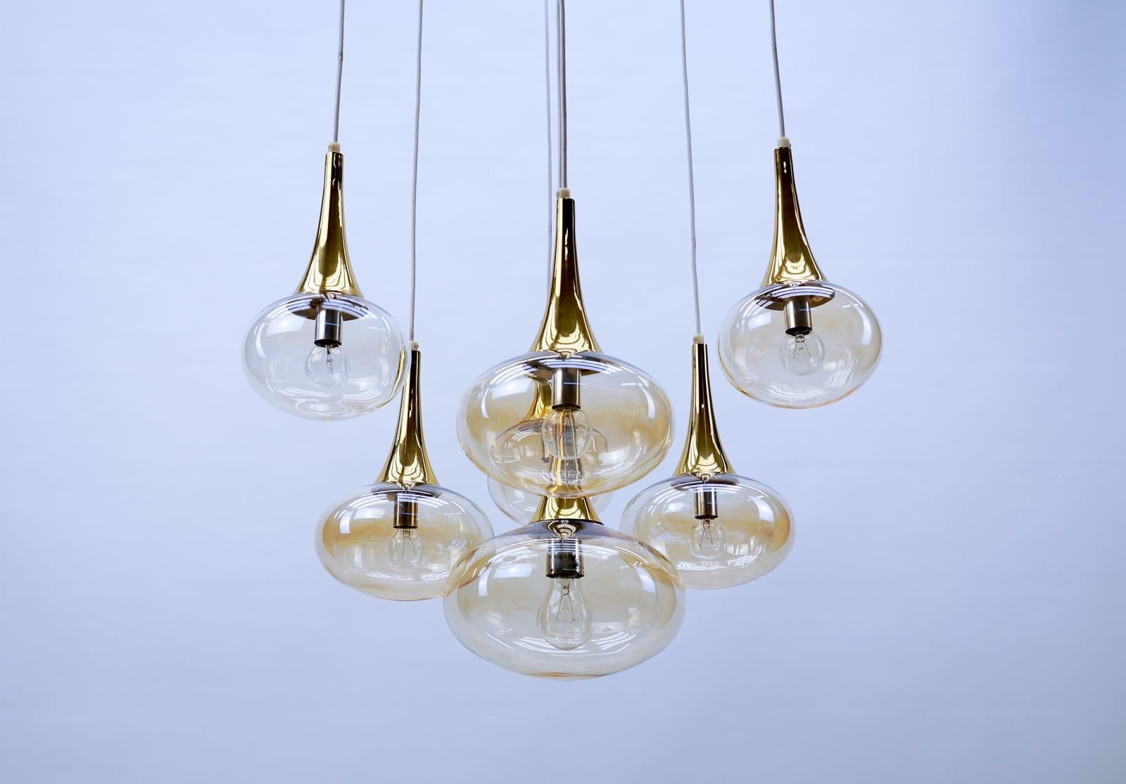 This ceiling lamp features a small frame with seven cascading glass elements with one E27 and six E14 bulb sockets.