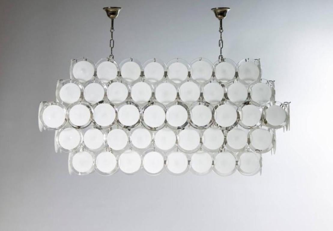 Eine zeitgenössische Murano-Glasaufhängung mit weiß-milchigen Tellern, entworfen von Giovanni Dalla Fina.
Diese verführerische Aufhängung aus Murano-Glas, die mit eleganten weiß-milchfarbenen Plättchen verziert ist, ist ein Beispiel für die