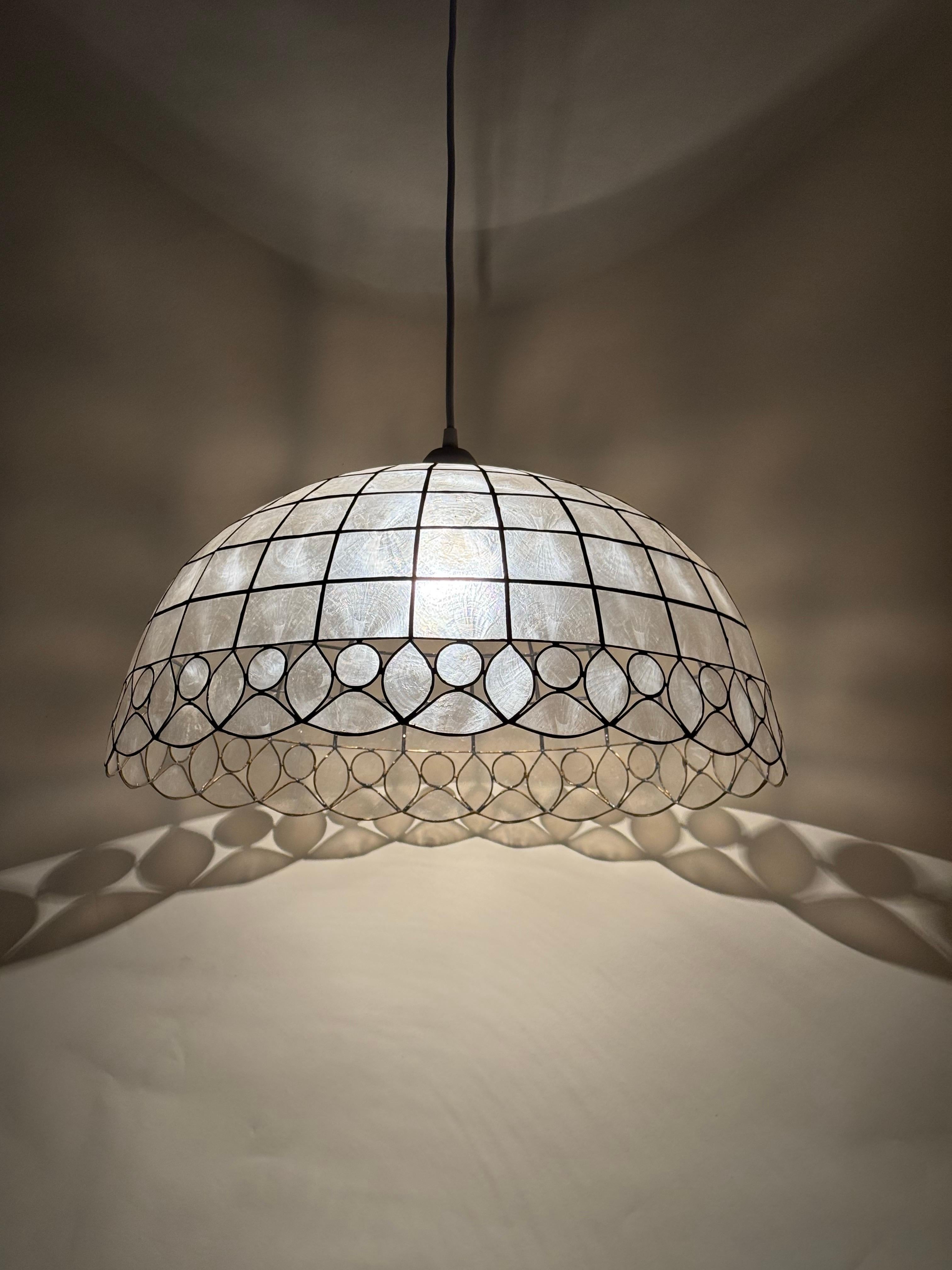 Diese aufwendig gestaltete Hängeleuchte wurde in liebevoller Handarbeit gefertigt, so dass jedes Stück ein echtes Unikat ist. Jede Capiz-Muschel wurde liebevoll von Hand geformt und die Lampe dann mit Messinglot von Hand zusammengesetzt, was an den