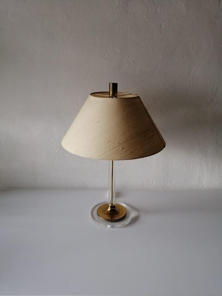 Fabric shade plexiglass and brass large table lamp by Leola, 1970s, Germany 

Plexiglass and brass body and base
The brass rod holding the lamp is placed in the plexiglass rod. Brass base is also placed on the plexiglass bigger base.

Very high