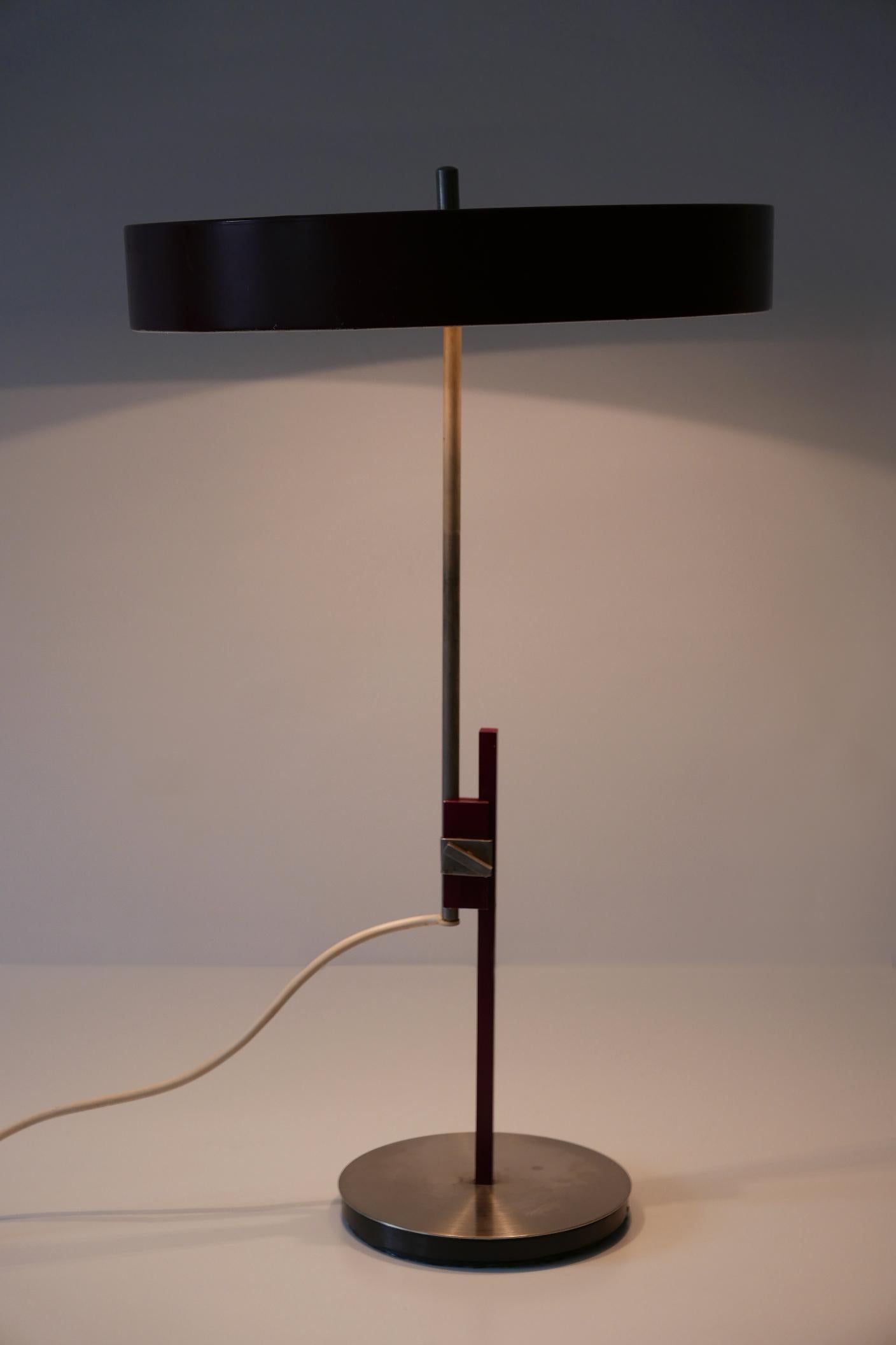 Gorgeous Mid-Century Modern luxury table lamp or desk light in Bordeaux color. Modell 6886. Manufactured by Kaiser Leuchten, 1960s, Germany. Adjustable in height.

Executed in Bordeaux enameled steel, nickel-plated brass tube, the desk light comes