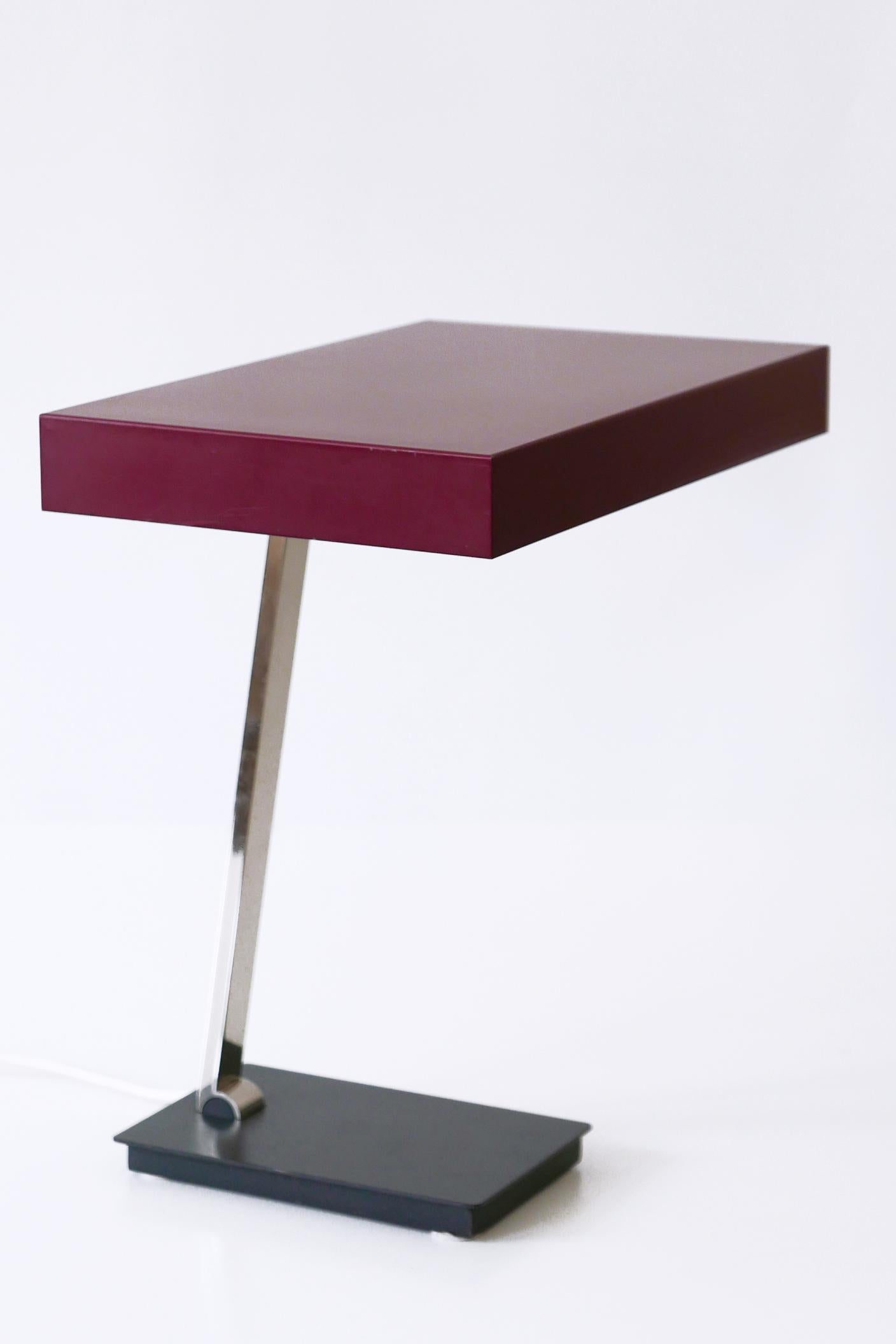 Gorgeous Mid-Century Modern luxury table lamp or desk light in Bordeaux color. Modell 6874. Manufactured by Kaiser Leuchten, 1960s, Germany. Adjustable arm and shade.

Executed in Bordeaux enameled steel, nickel-plated brass tube, the desk light
