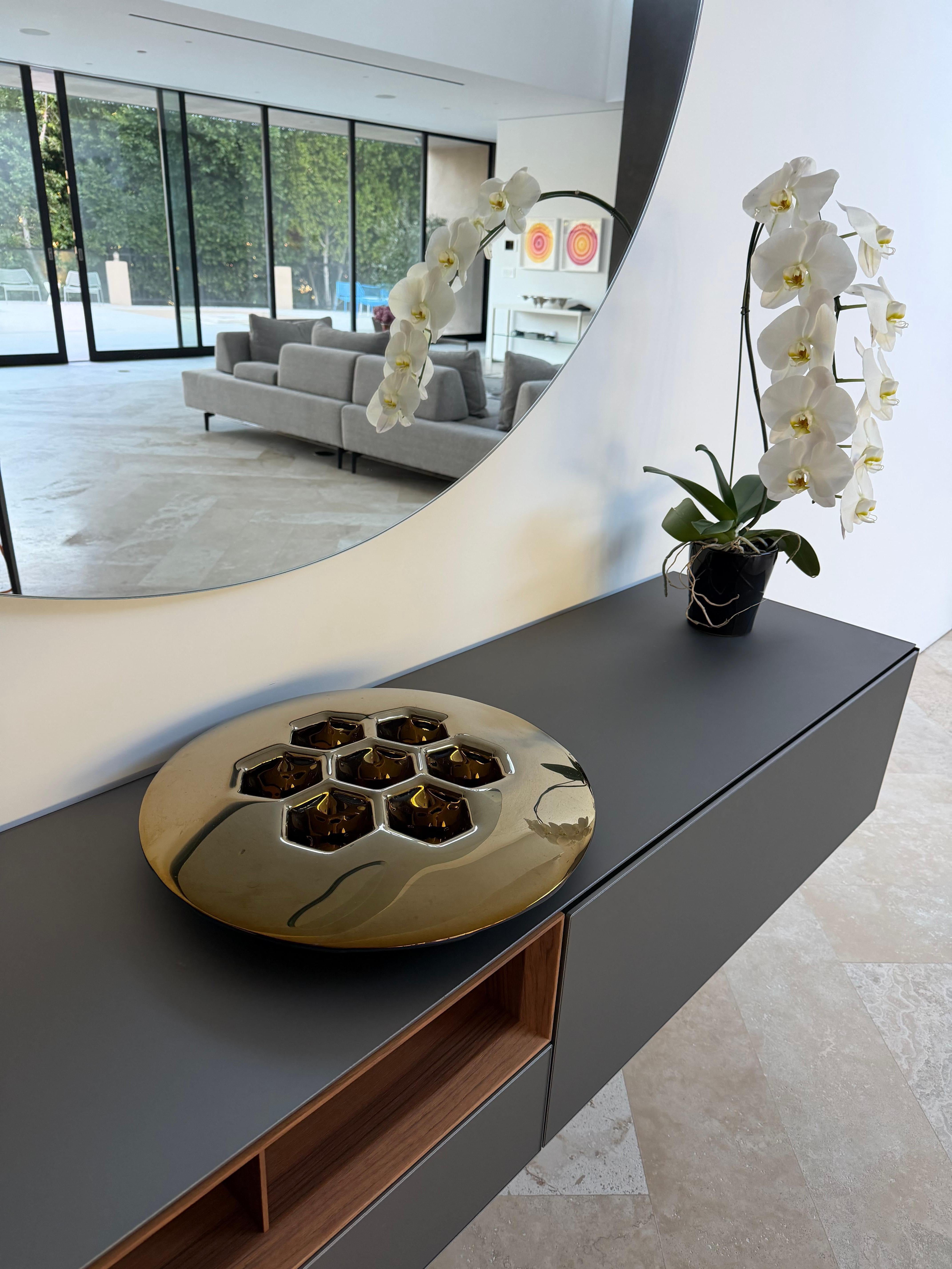 PlusObject formt die Cells-Textur im Brennofen und überzieht sie dann mit goldfarbenem Titan, um eine dekorative Schale in Goldoptik zu schaffen. Der 490-mm-Teller wiegt 4 kg (8,8 lb), ist 7 cm (2,7 in) hoch und wirft warme Reflektionen an die nahe