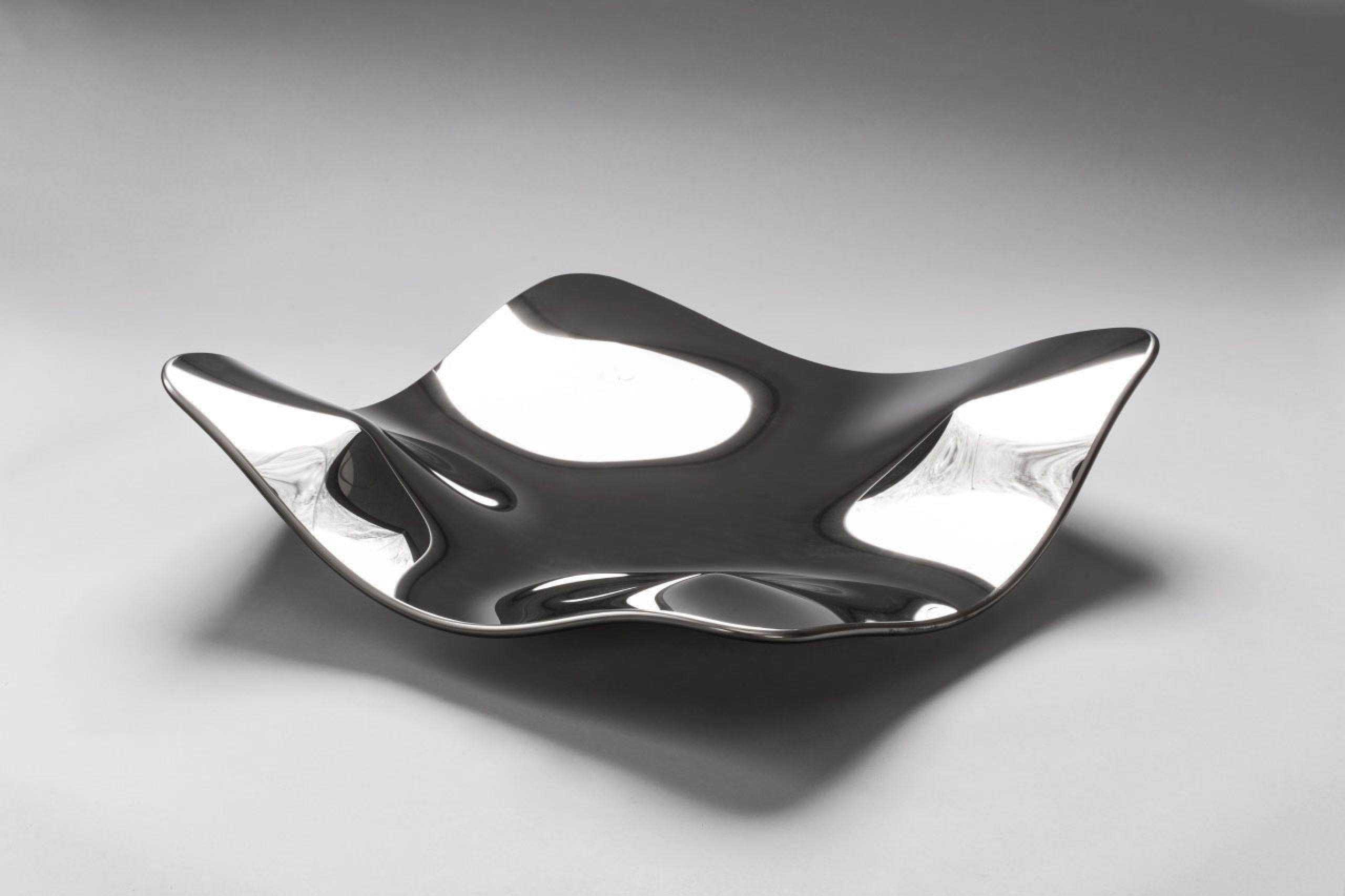 Le Manta Silver Platter se répand en flottant comme une raie sur le corail tandis que le noyau le verrouille. Les sculpteurs sur verre font glisser la feuille sur un moule en céramique, dessinant des canaux fluides qui diffusent des reflets en
