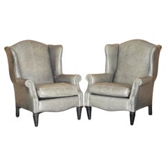 Paire de fauteuils de luxe contemporains en cuir gris et bleu à dossier pivotant, avec pieds en bois.