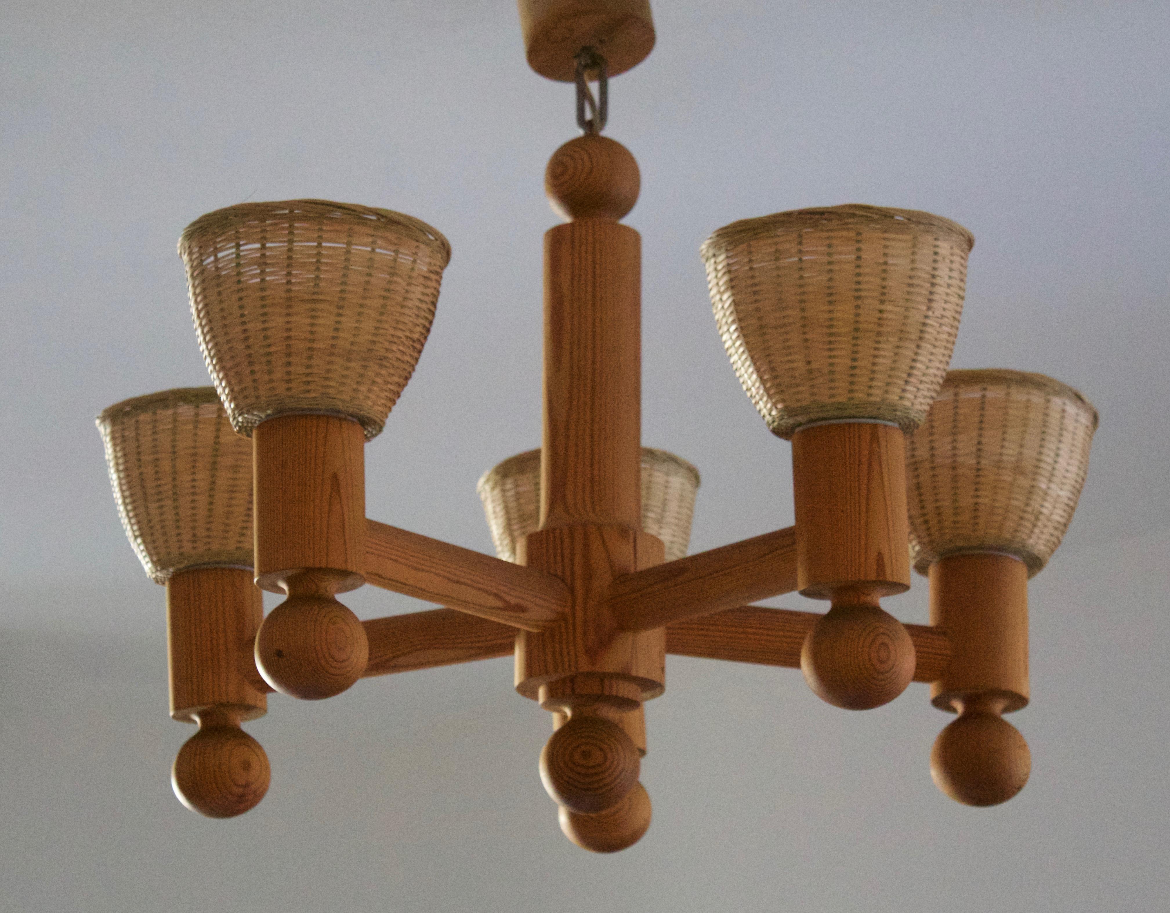 A chandelier light. By Luxus, Sweden, 1970s. In solid pine. Assorted vintage rattan lampshades.

Five-armed. Stated height includes full drop.

Other designers of the period include Axel Einar Hjorth, Roland Wilhelmsson, Charlotte Perriand,