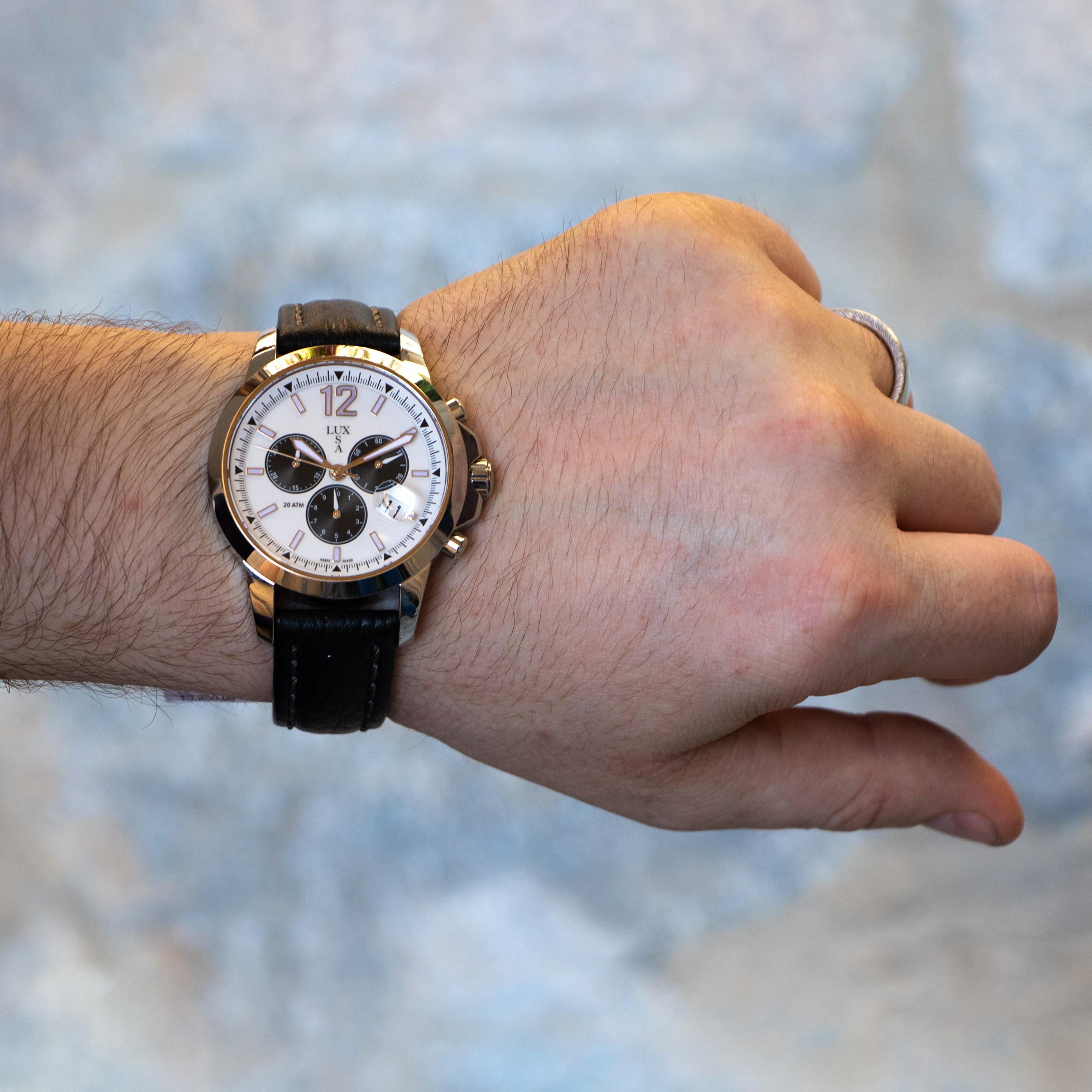 Beautiful stainless steel watch with a white face and black leather strap. This watch has a magnified date window and features chronograph capabilities - 3 miniature dials that keep track of milliseconds, seconds, and minutes which are all Swiss
