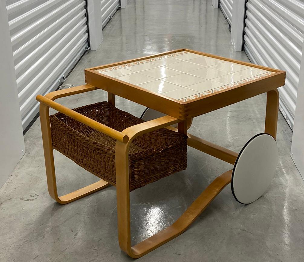 The tea trolley 900, which features ceramic tiles and a rattan basket, was first exhibited at the World Exhibition in Paris in 1937, a traditional piece of furniture done with a modernist design Tea Trolley 900 is the perfect barcart for enjoying