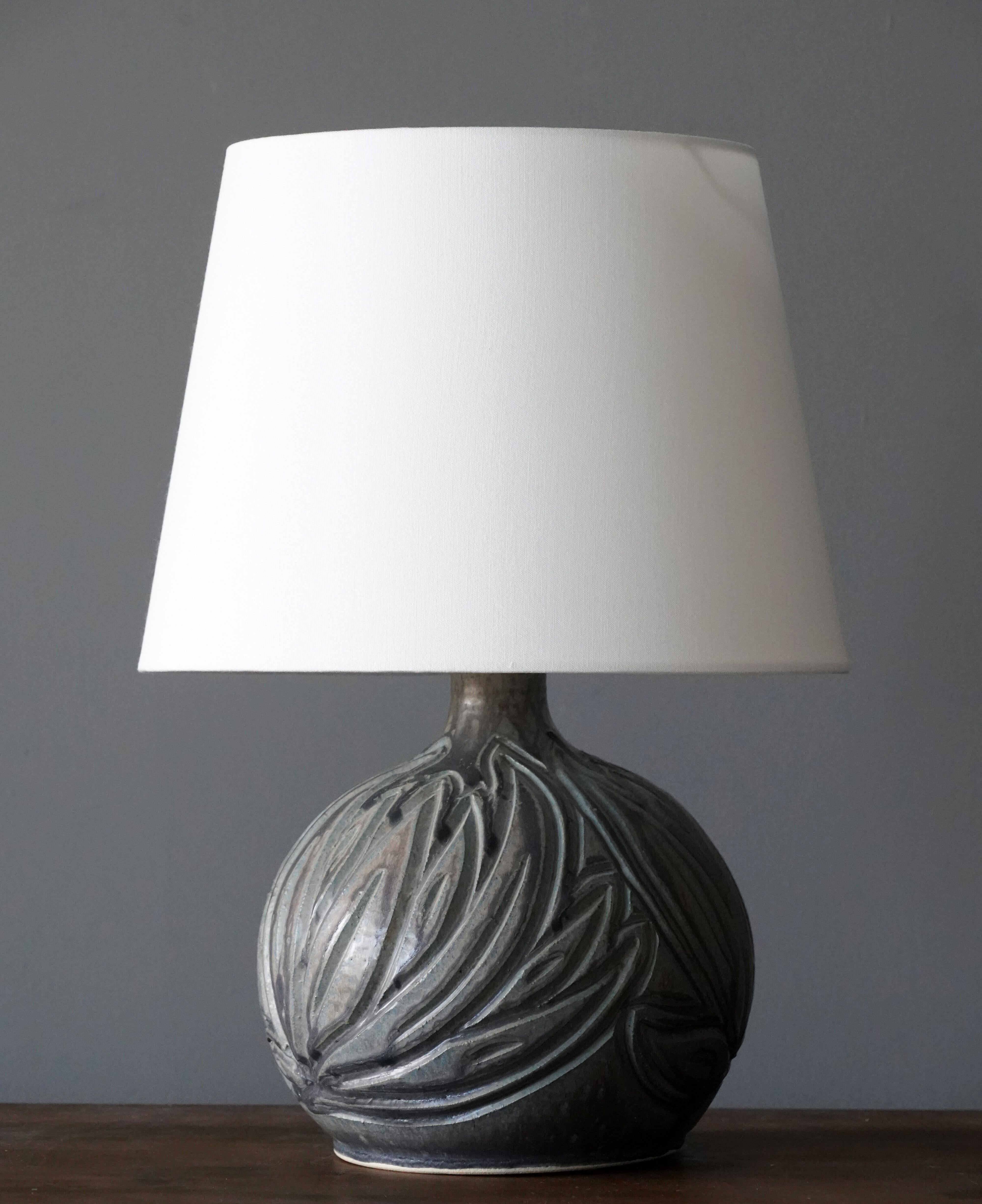 An organic table lamp produced and designed by Løvemose, Denmark, 1960s. With makers label.

Lampshade is attached for reference and are not included in the purchase. Measured without lampshade.

Glaze features grey-green colors with hints of