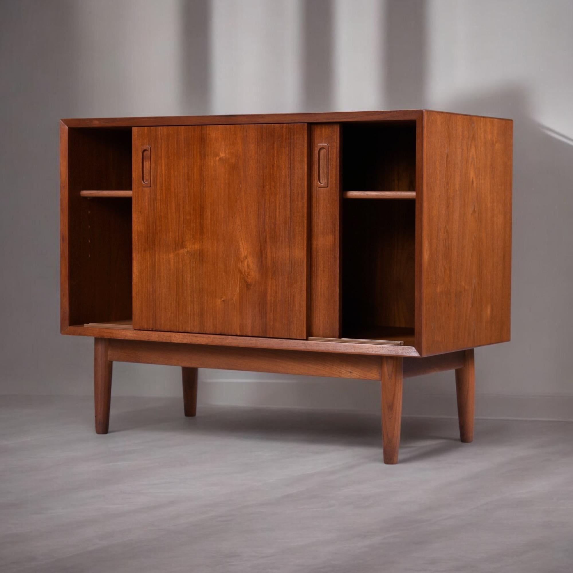 Raffinato esempio di artigianato danese, questo mobile ad ante scorrevoli in teak di Lyby Møbler cattura la tranquilla raffinatezza che contraddistingue il design moderno scandinavo. La sua forma minimalista è sostenuta da una falegnameria precisa e