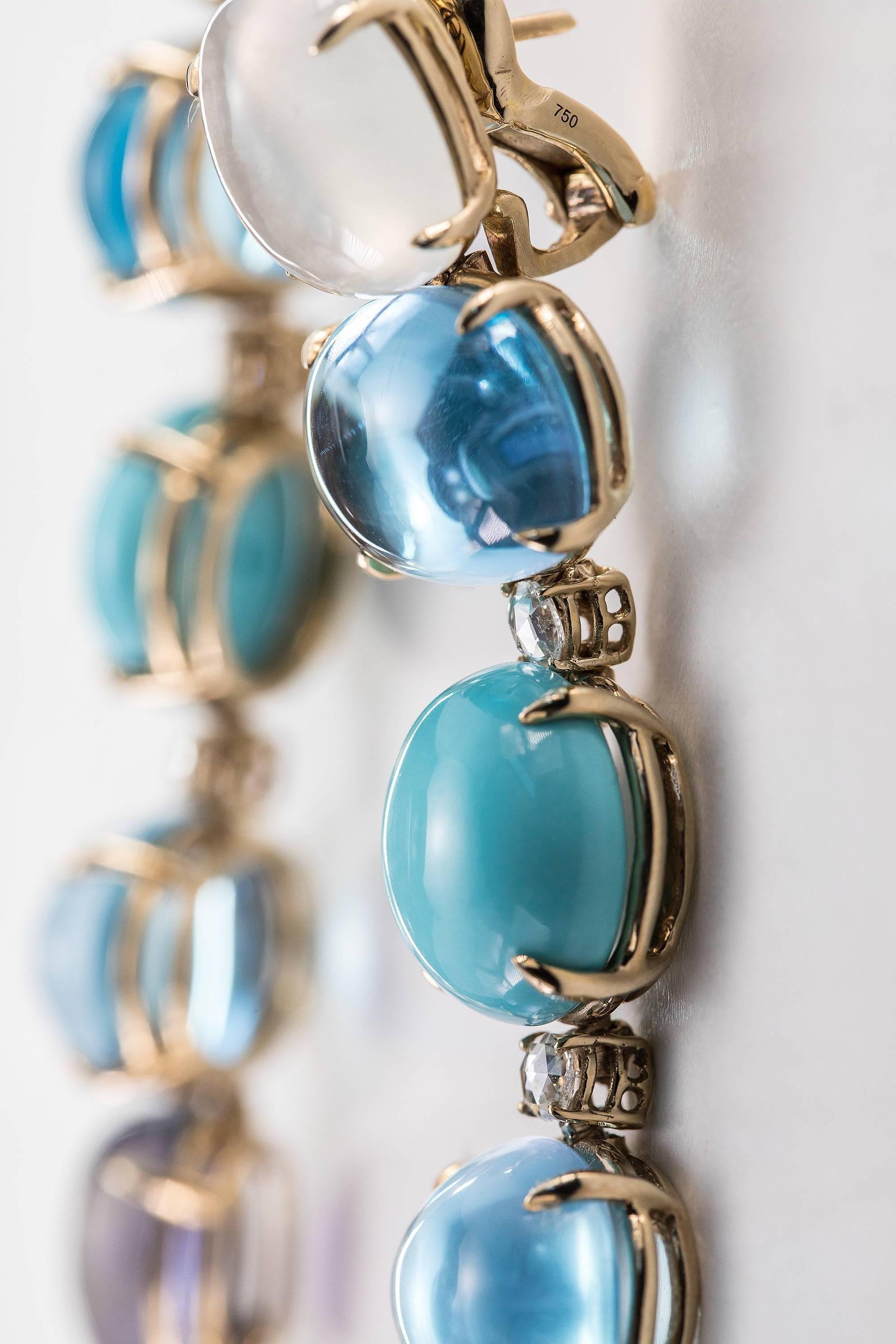 The Earrings are One of a Kind, designed by Lygia Demades as a Blue Rainbow in a flexible hand made 18kt gold setting in Sand color specifically created to enhance the color of the stones and look subtle and elegant when worn next to the skin.