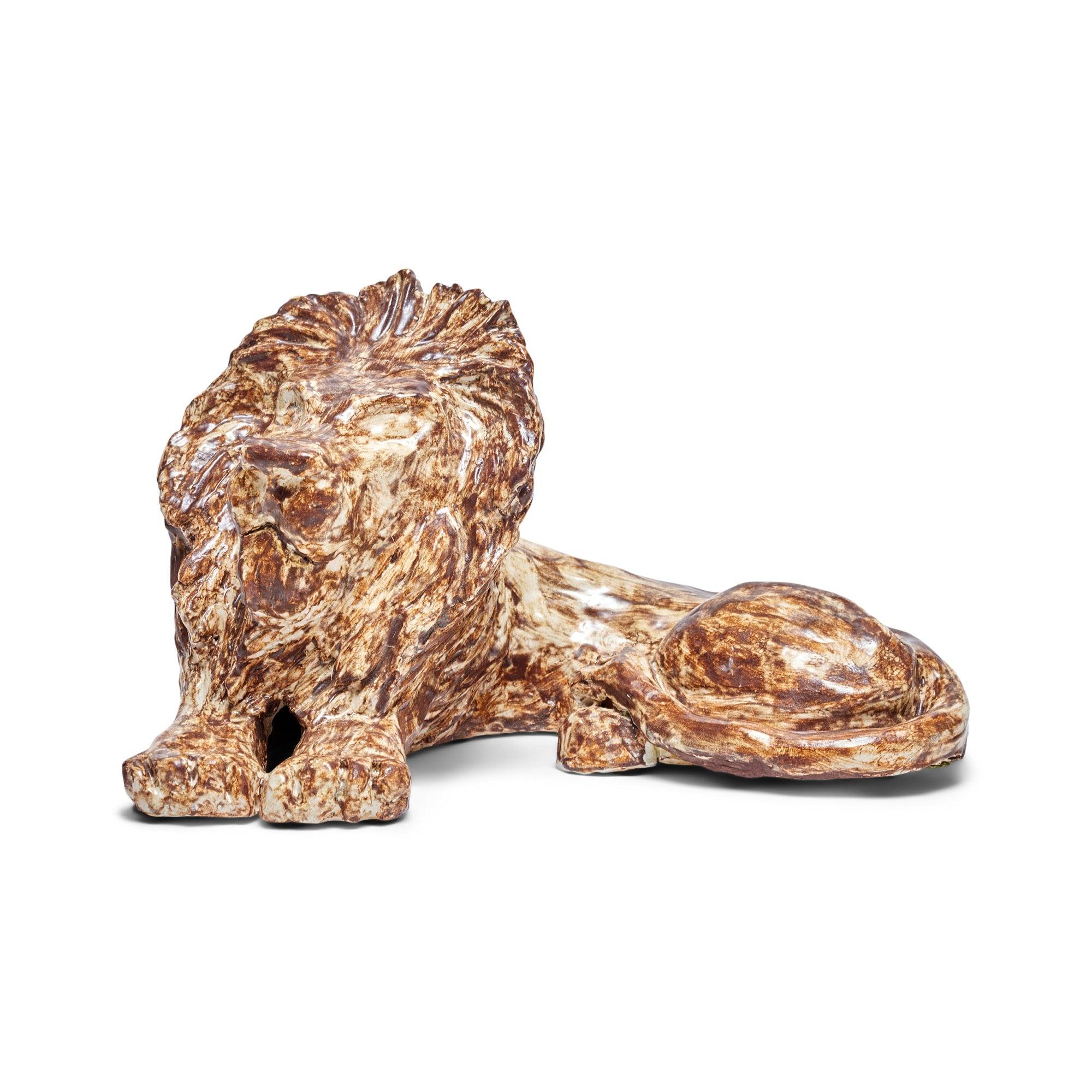 Un'impressionante scultura in ceramica raffigurante un leone sdraiato, con un ricco smalto opaco di grande consistenza.