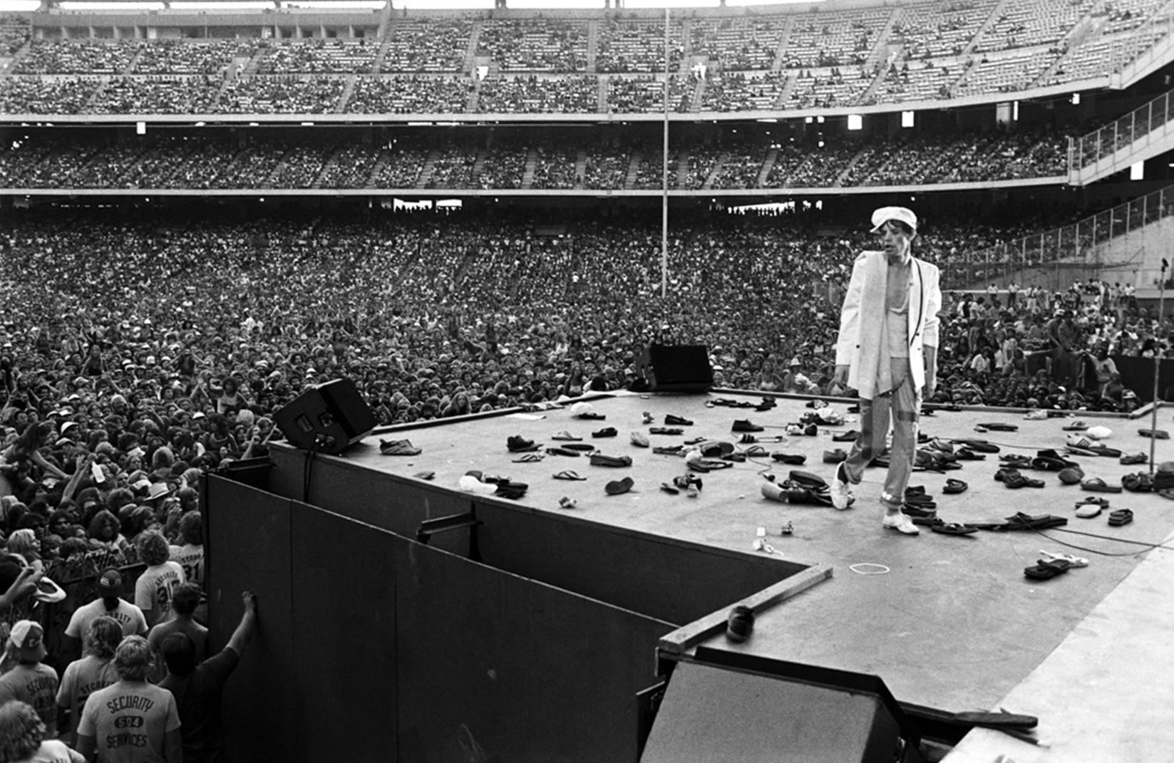 20”x24” signed limited edition print of Mick Jagger of The Rolling Sones surrounded by boots that had been thrown on the stage by fans in 1978 by Lynn Goldsmith, signed and numbered #10/20.